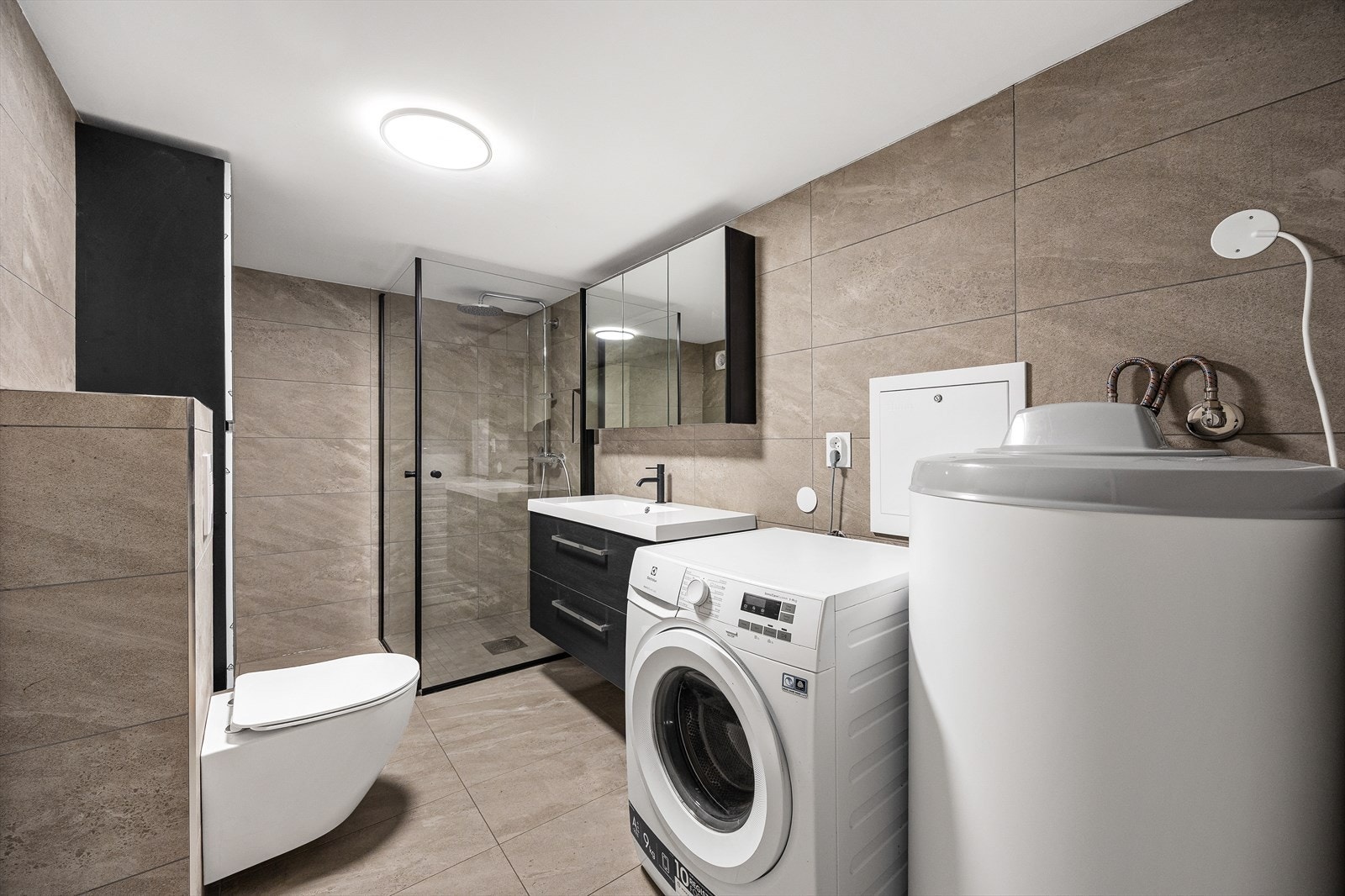 Badet i kjelleren er fra 2025, med fliser på gulv og vegger. Galleribilde
