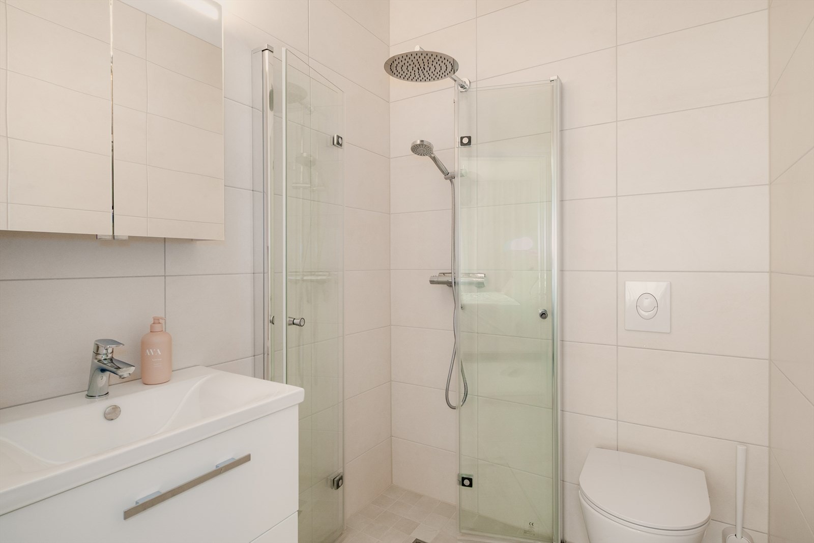 Flott helfliset bad med varmekabler i gulv. Badet er utstyrt med servant med innredning, dusj og vegghengt toalett. Galleribilde