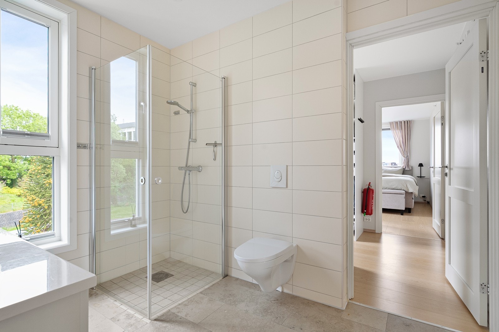 Badet inneholder vegghengt toalett, dusj og baderomsinnredning. Galleribilde