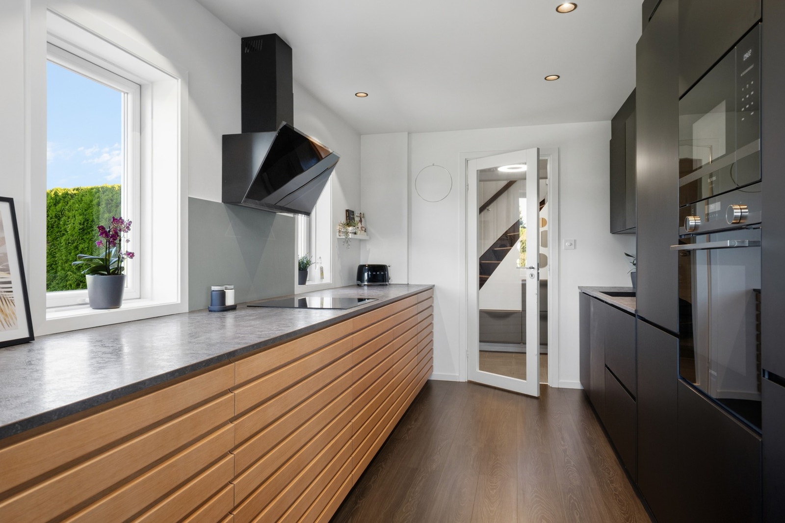 Kjøkkenet er utstyrt med integrert induksjonstopp, stekeovn, mikrobølgeovn, oppvaskmaskin og kjøl/frys, samt en ventilator med sort glassfront over kokesonen. Galleribilde