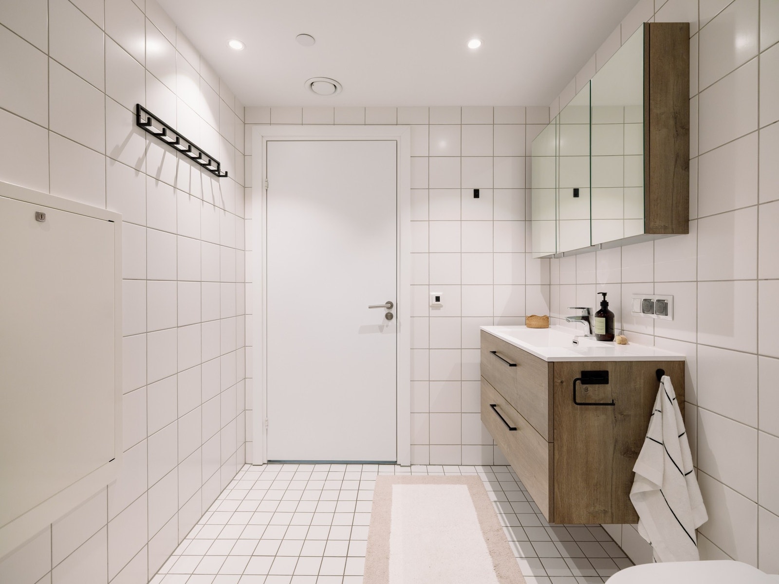 Et stilrent bad som kombinerer funksjon og estetikk, med downlights i himling og pent designet servant med overskap. Galleribilde