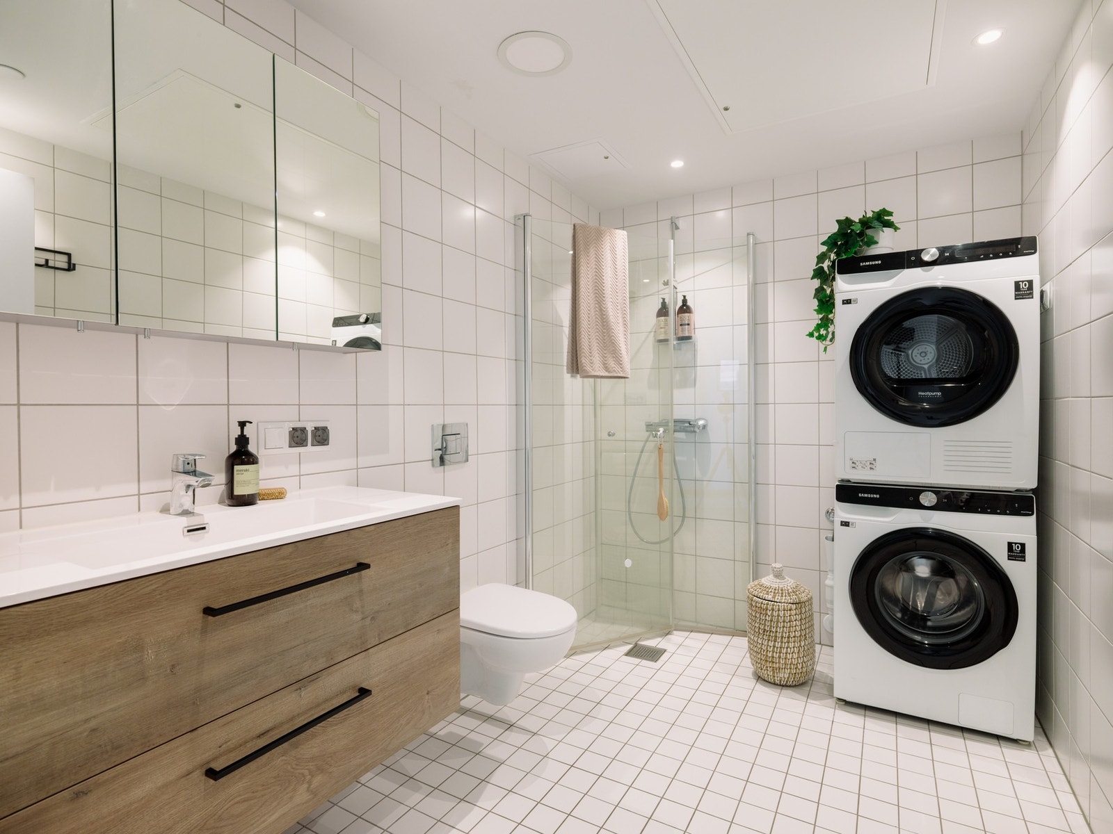 Moderne, flislagt bad med dusj og tilrettelegging for vaskemaskin og tørketrommel. Galleribilde