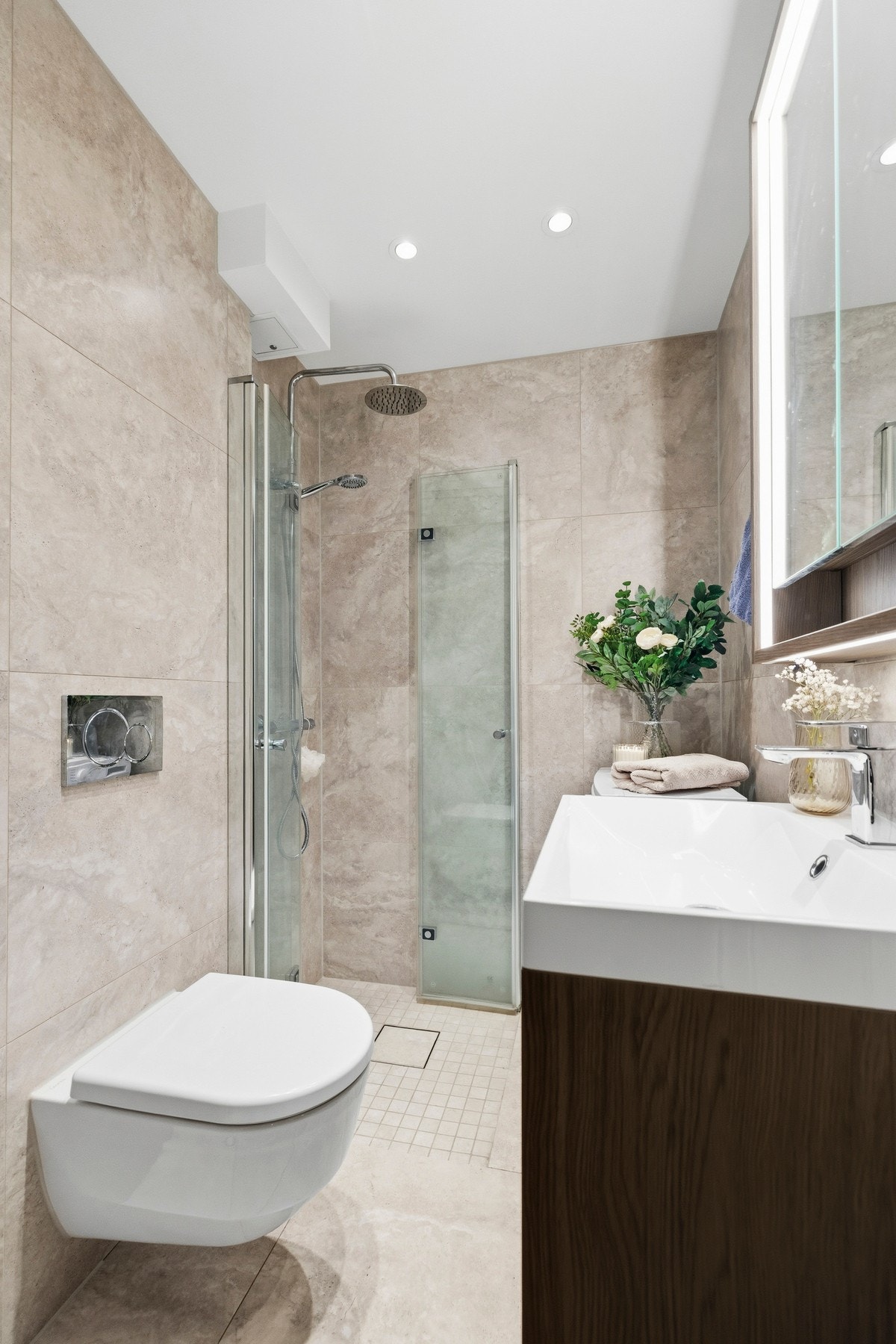 Badet fremstår moderne og funksjonelt med innredning med nedfelt servant, vegghengt toalett, dusjhjørne med praktiske foldedører i glass samt opplegg for vaskemaskin. Galleribilde