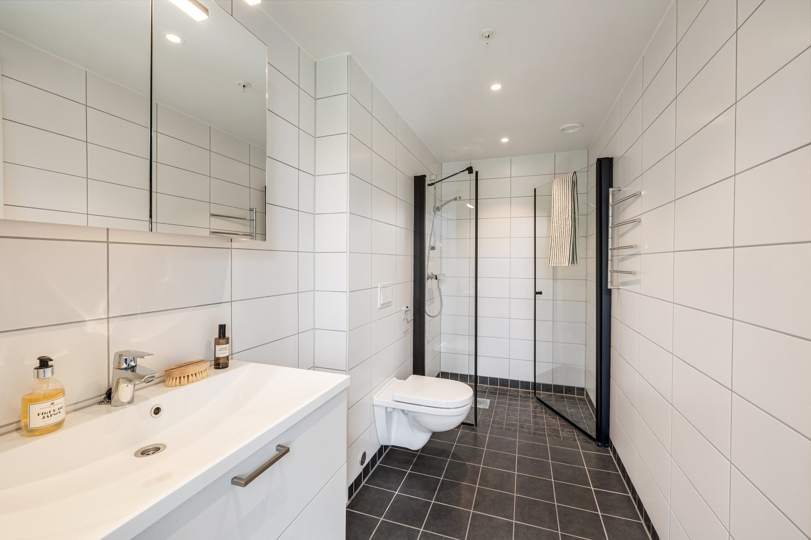 Badet har samme moderne standard som øvrige våtrom i boligen, med flislagte overflater og gulvvarme. Dette gir en eksklusiv og privat hotellfølelse i hverdagen Galleribilde