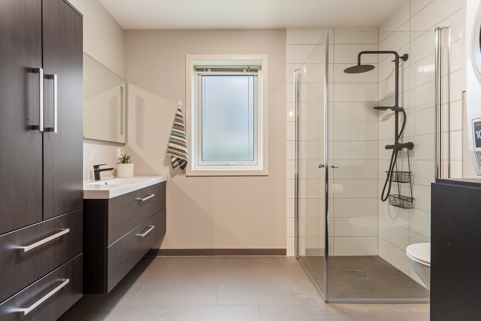 Badet i 1. etasje er innredet med vegghengt toalett, opplegg vaskemaskin og dusjhjørne med innfellbare glassdører. Galleribilde