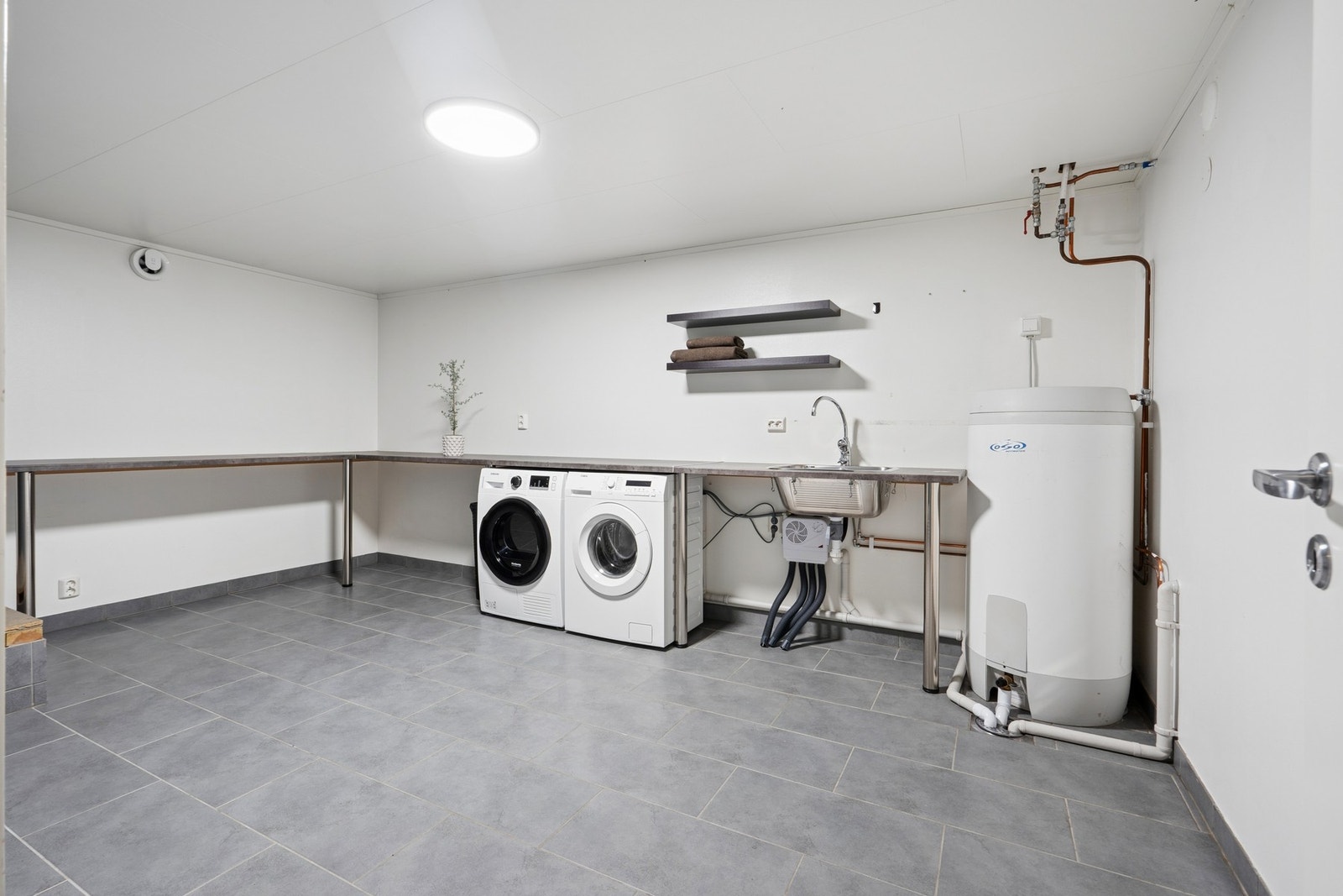 Stort vaskerom oppgradert i 2012, med flislagt gulv med varmekabler, benkeplate med utslagsvask og opplegg for vaskemaskin. Galleribilde