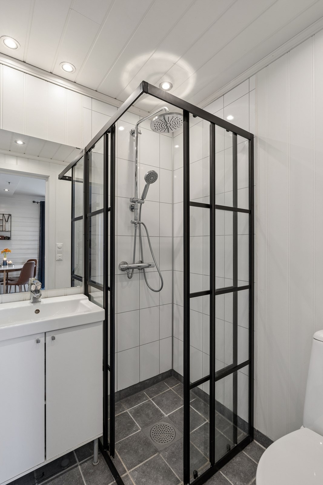 Badet har flislagt gulv med gulvvarme og en stilren dusjnisje. Galleribilde