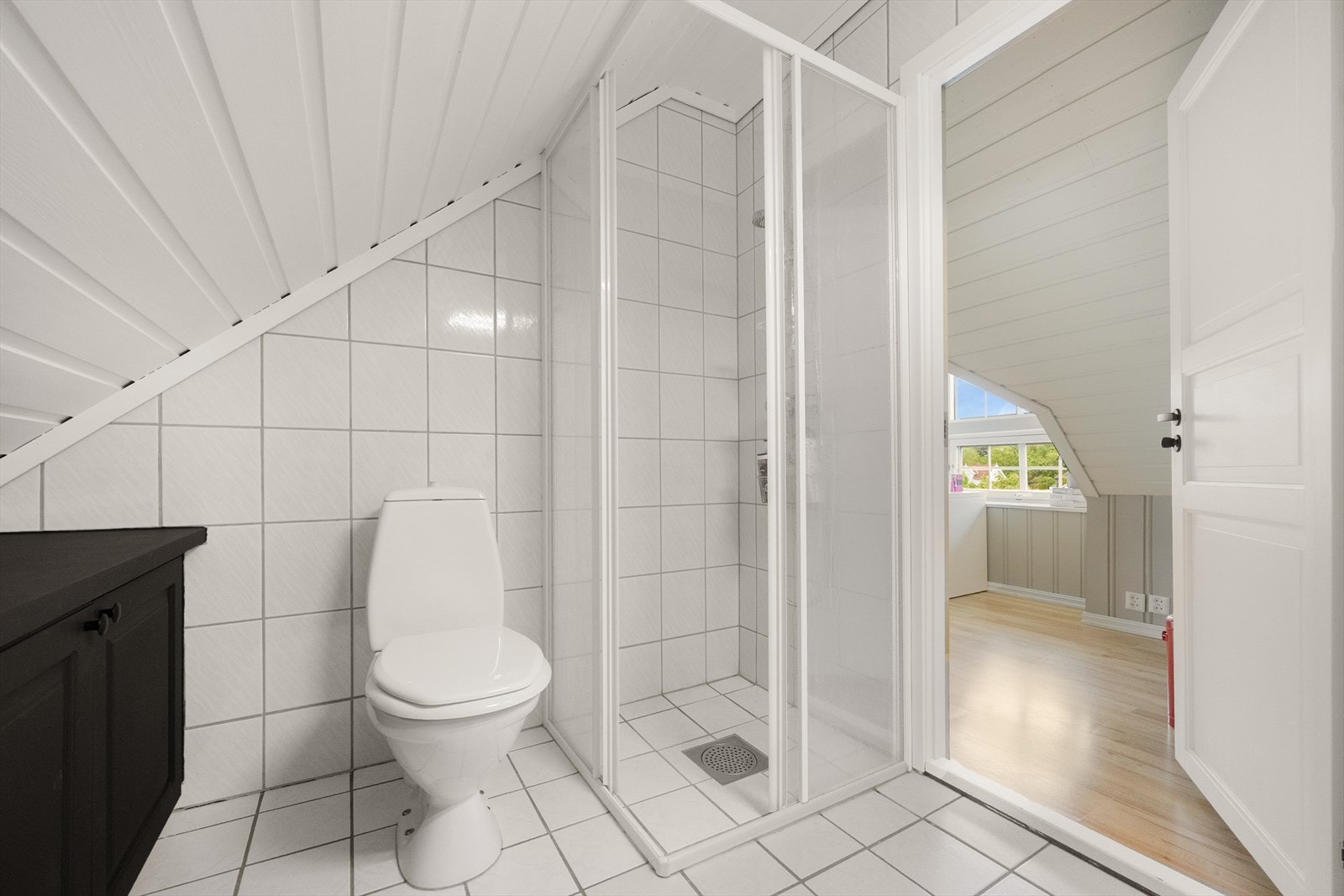 Badet er utstyrt med dusjhjørne med glassdører, toalett og servantinnredning. Galleribilde