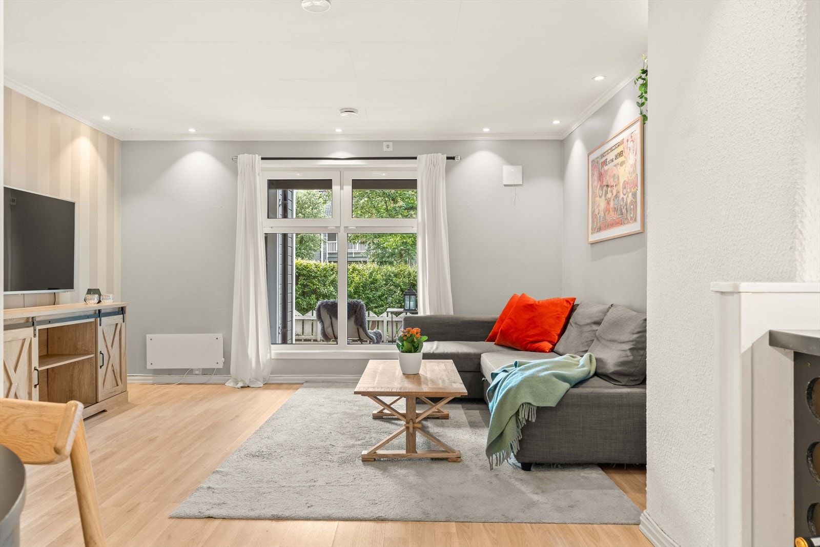 Stua er lys og luftig med store vinduer, lyse veggflater og downlights i himling. Galleribilde