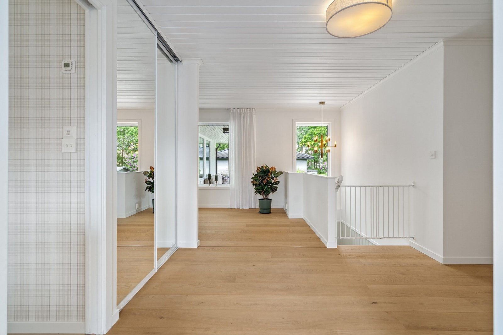 Romslig og innbydende hall med skyvedørsgarderobe samt trapp ned til underetasjen Galleribilde