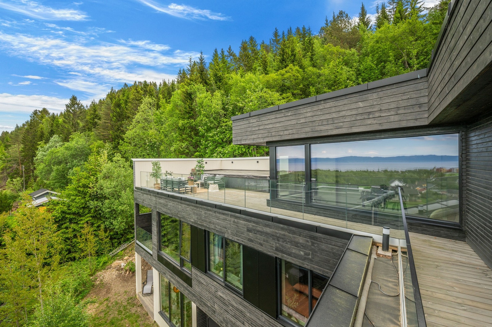 Takterrassen er tilrettelagt for motstrømbasseng. Eiendommen sett fra luften på sommeren. Galleribilde