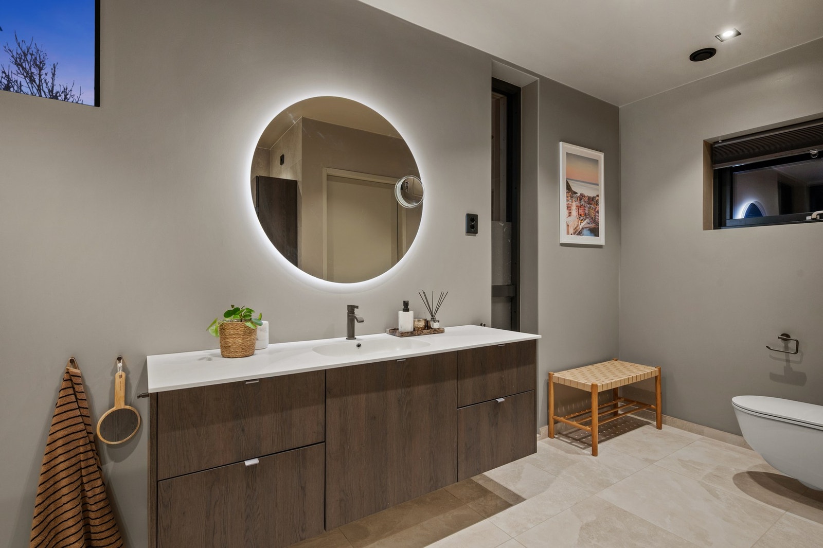 Masterbad med storformat Rock Salt White Gold fliser fra Nordfloor, HTH baderomsinnredning med Corian benkeplate og Tapwell-armaturer. Rundt speil med baklys og tilrettelegging for badekar - gjennomført og tidløst. Galleribilde