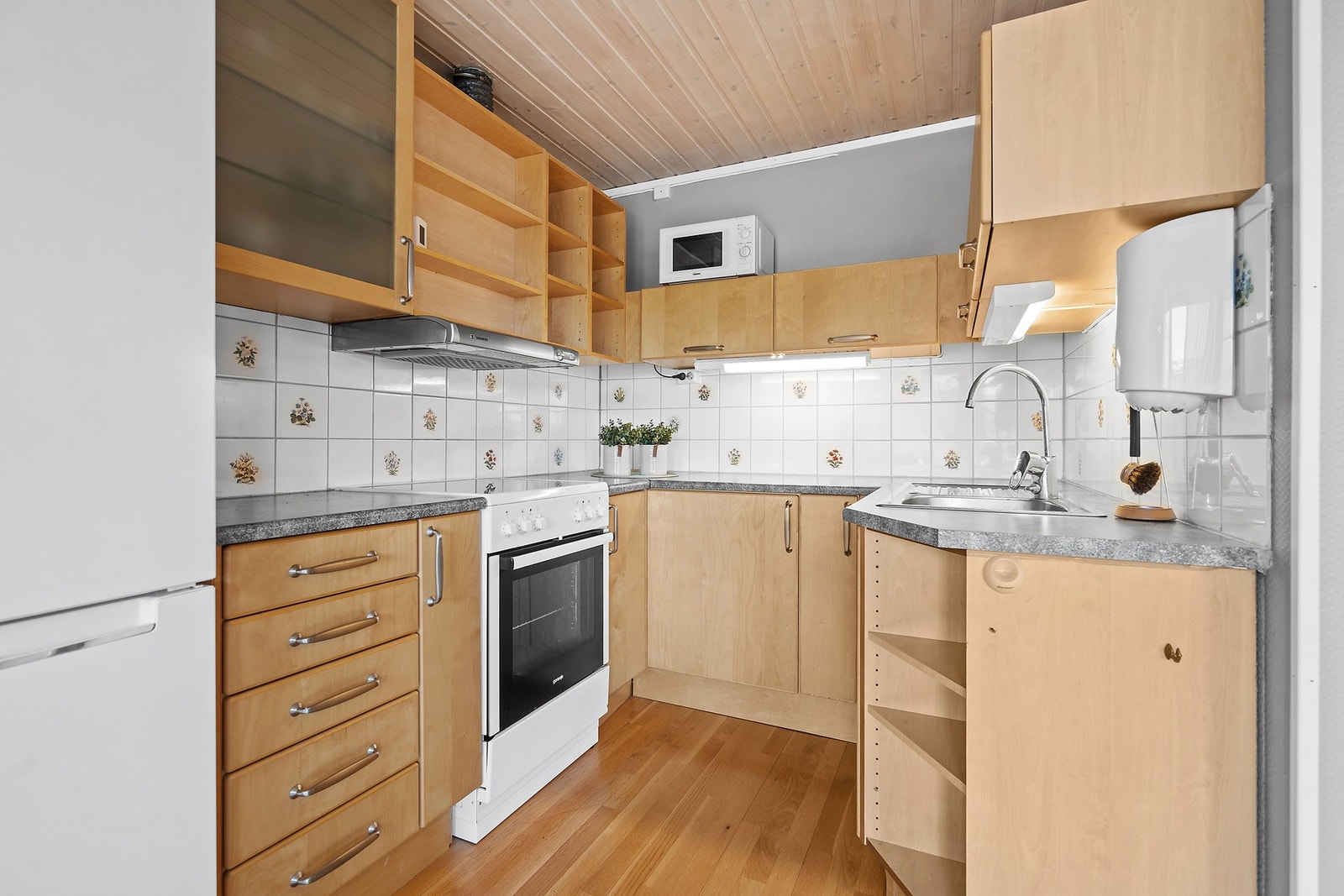Kjøkkeninnredning med glatte fronter, laminatbenkeplate og kjøkkenventilator med avtrekk ut. Galleribilde
