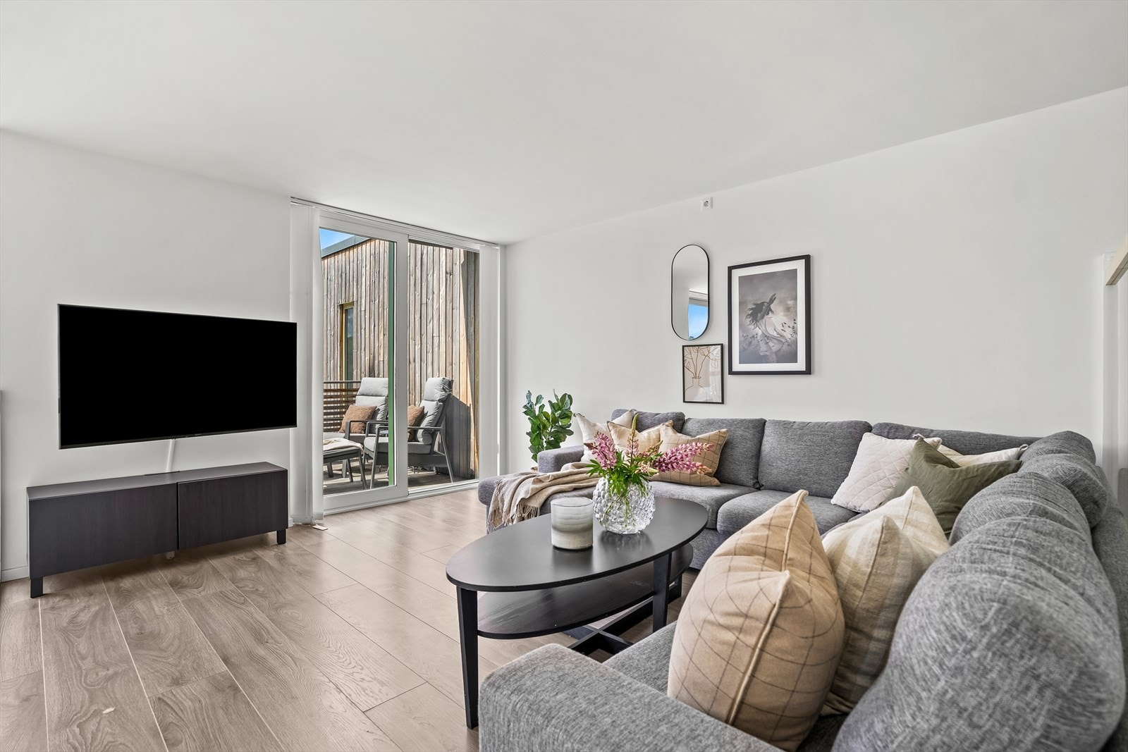 Stuen er innredet med stor sofa og gir adkomt til solrik balkong. Galleribilde