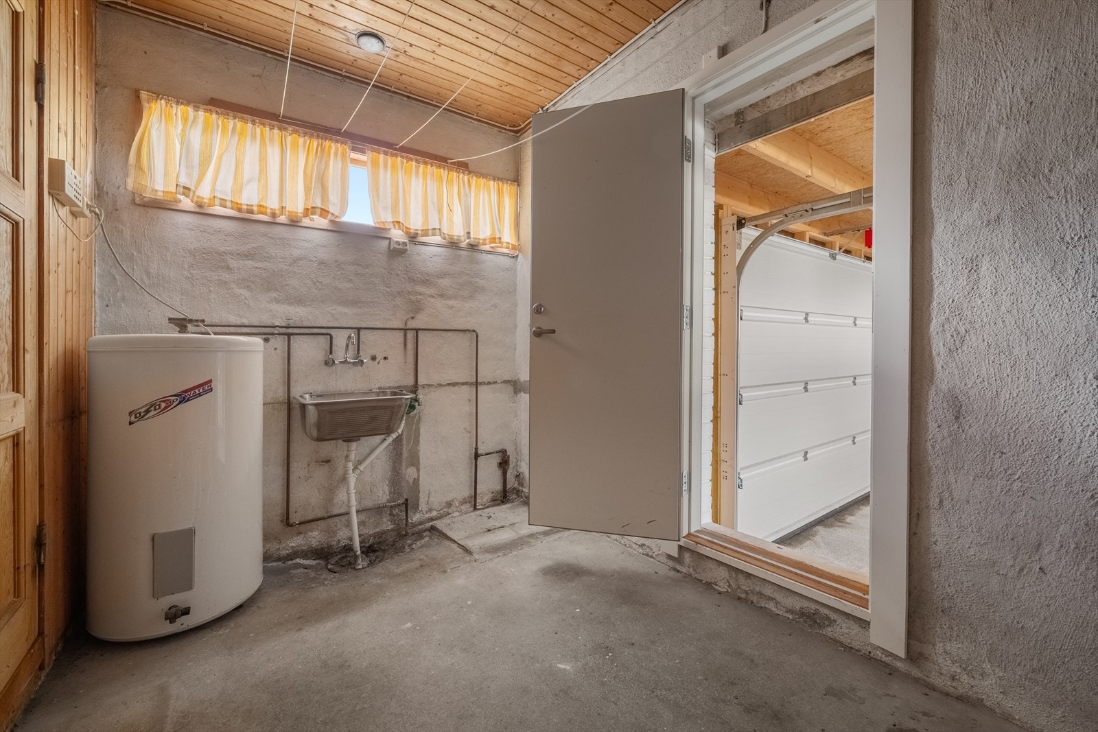 Praktisk vaskerom med utslagsvask, opplegg for vaskemaskin og adkomst til garasjen. Galleribilde