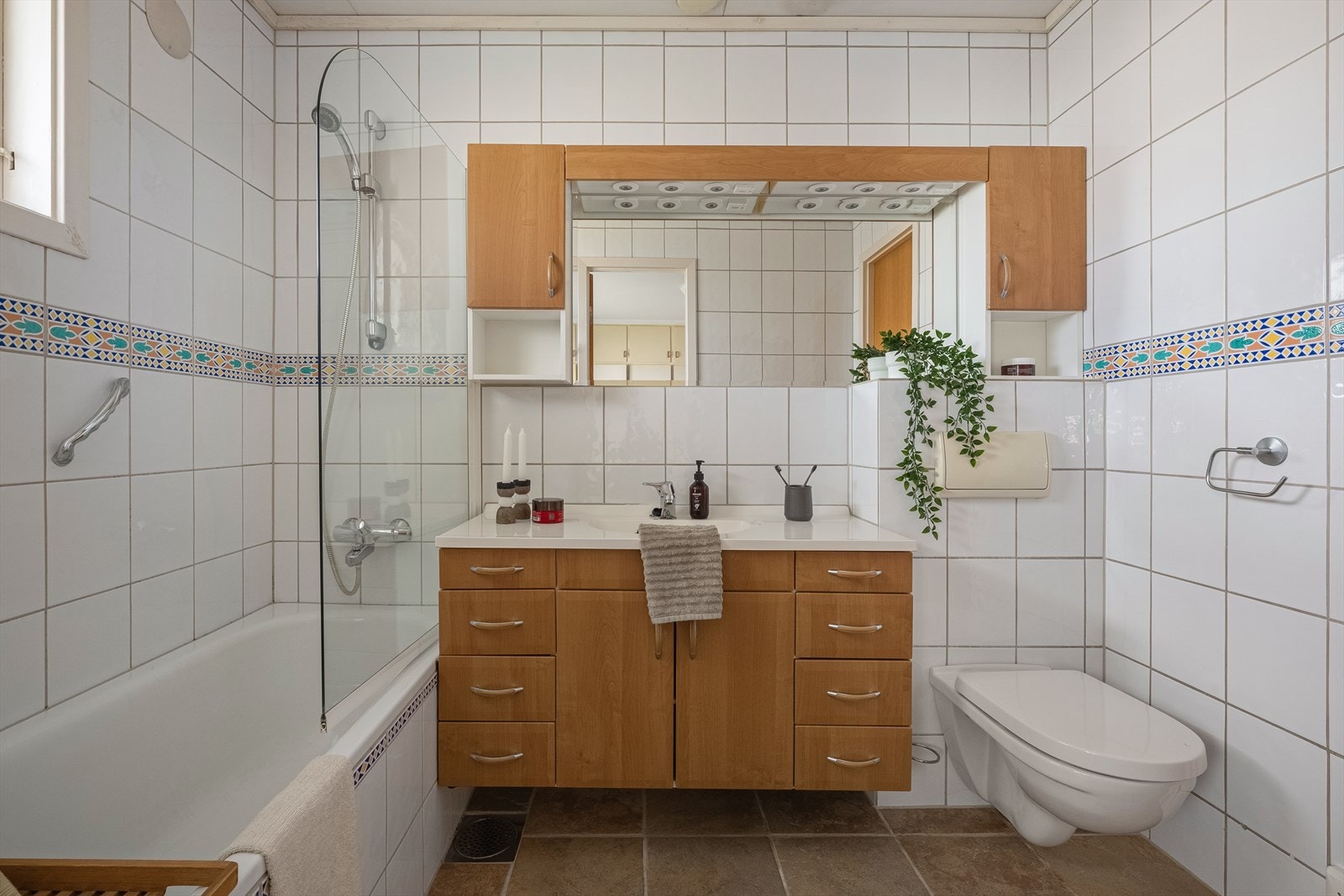 Badet er innredet med badekar, veggmontert toalett og servant med underskap. Galleribilde