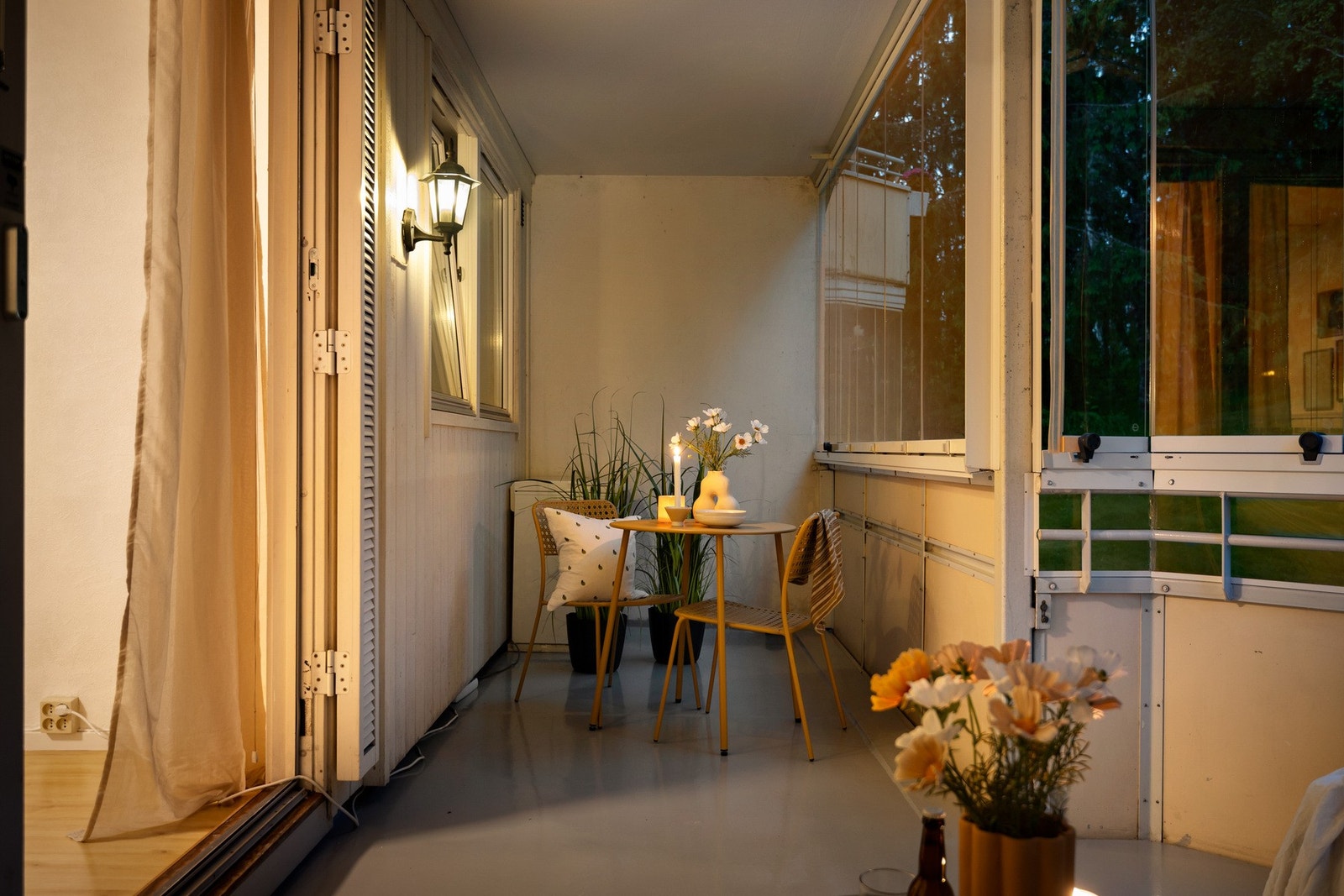 Kveldsstemning på balkongen - tent lys, blomster og en sittegruppe som innbyr til å slå seg ned. Galleribilde