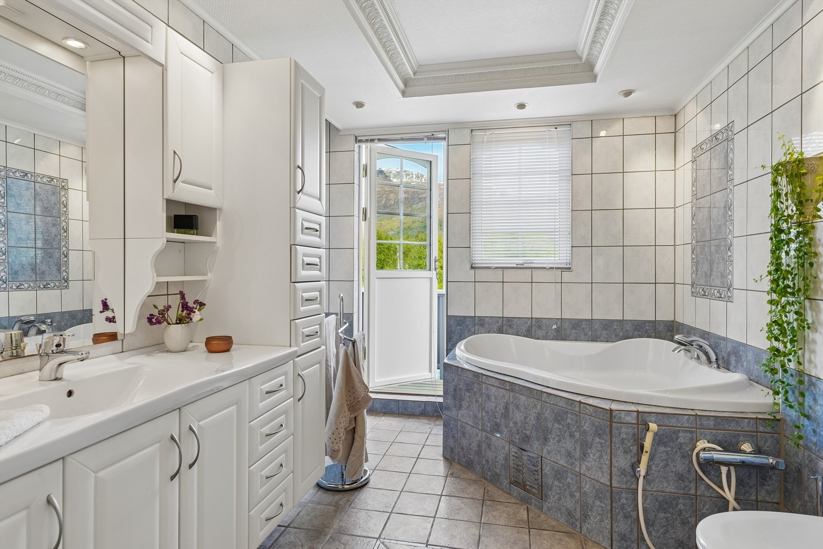 I etasjen er det et stort bad med flislagte vegger og flislagt gulv med varmekabler. Her er det innholdsrik baderomsinnredning, innfliset badekar, dusj og toalett. Fra badet er et utgang til en mindre veranda. Galleribilde
