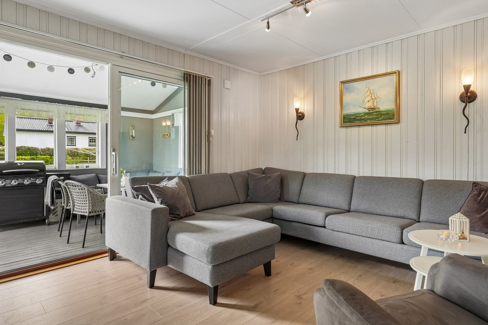 Fra stua er det en stor skyvedør i glass ut til en koselig, overbygd og delvis innbygd del av terrassen. Galleribilde
