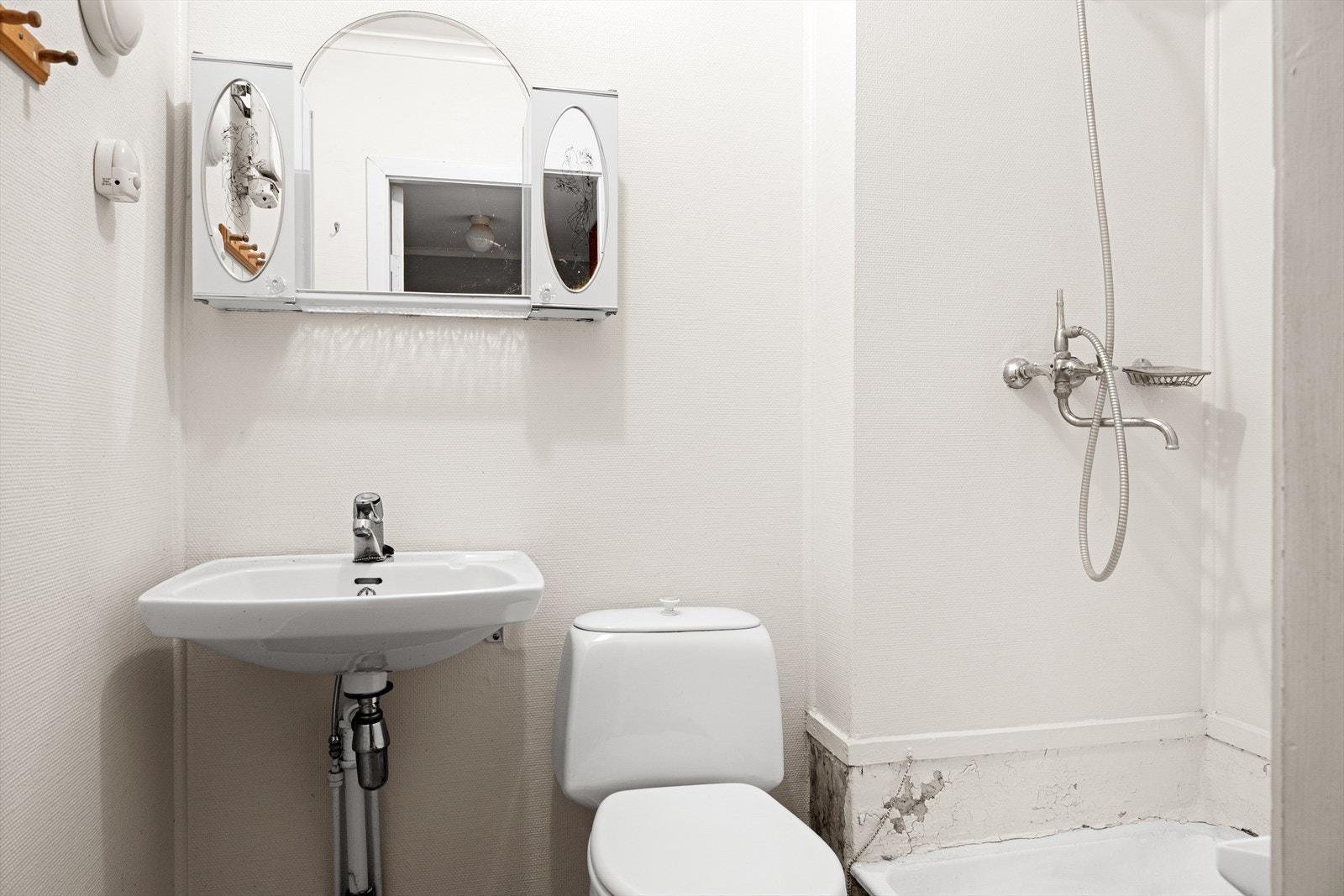 Badet er utstyrt med frittstående toalett, vegghengt vask og dusjhjørne. Galleribilde
