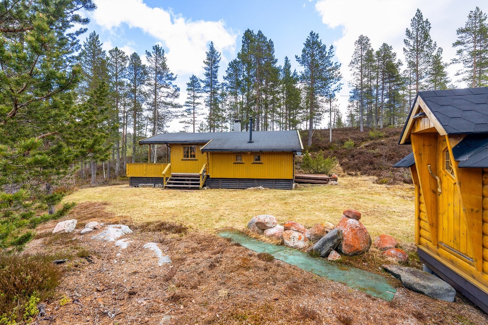 Eiendommen har en 1079.1 kvm stor naturtomt med blant annet trær og lyng, samt sjarmerende fjellknauser og terrasse ved hyttevegg. Galleribilde