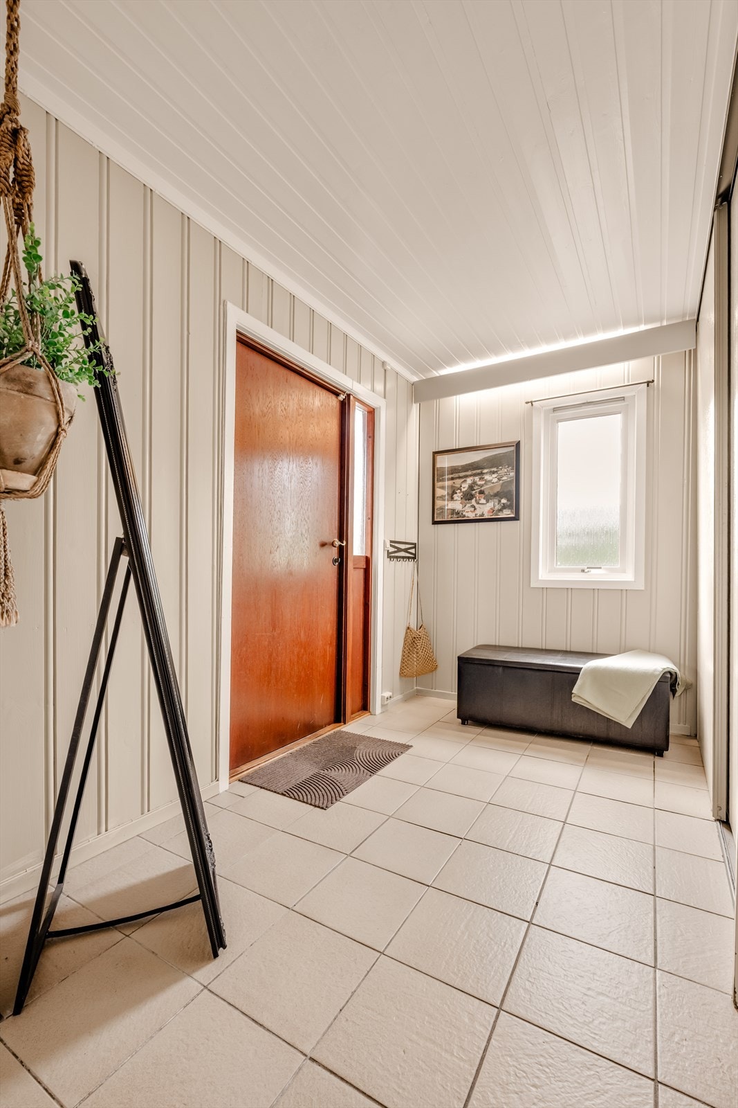 Velkommen inn! Entréen har flislagt gulv og vegger med malt panel. Galleribilde