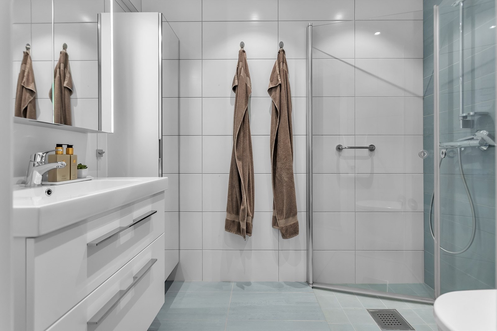 Badet har innredning med nedfelt servant, veggmontert toalett og dusjvegger/hjørne. Det er mekanisk avtrekk. Galleribilde