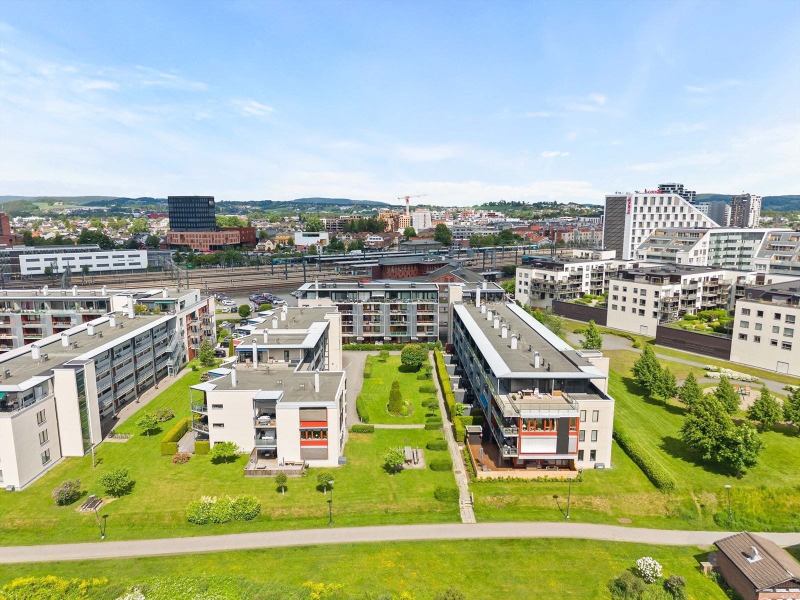 Moderne boområde med store, opparbeidede grøntarealer mellom bygningene. Galleribilde