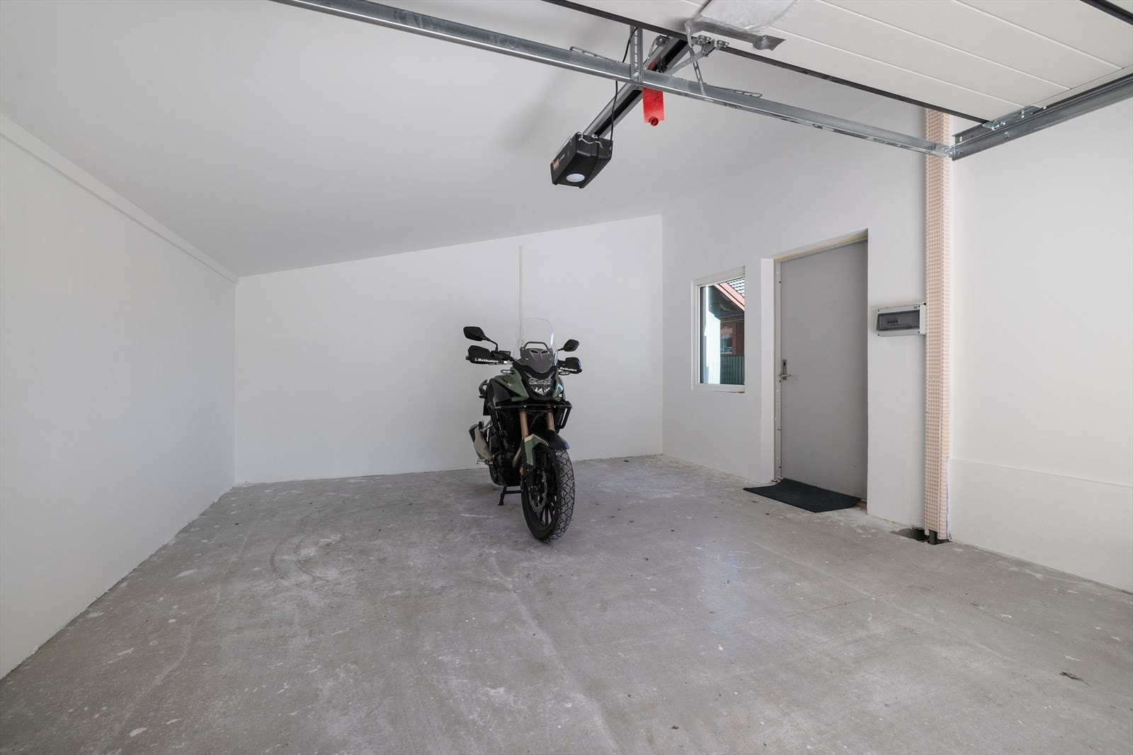 Garasjen er integrert i boligen og er av nyere dato, med elektrisk port. Trekkerør for kabel til elbil-lader og trekkerør for installering av solcellepanel fra sikringsskap og ut til vegg i garasje. Galleribilde