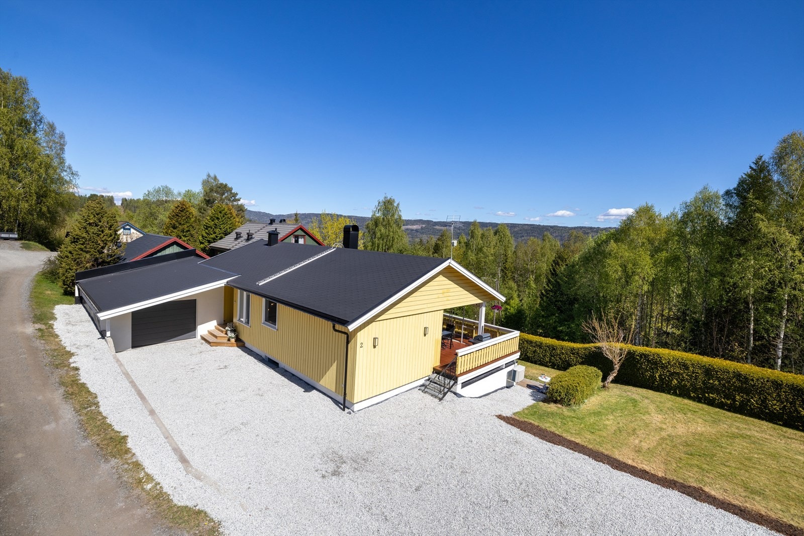 Stor, gruset gårdsplass med parkering for flere kjøretøy. Nyere, integrert garasje. Galleribilde