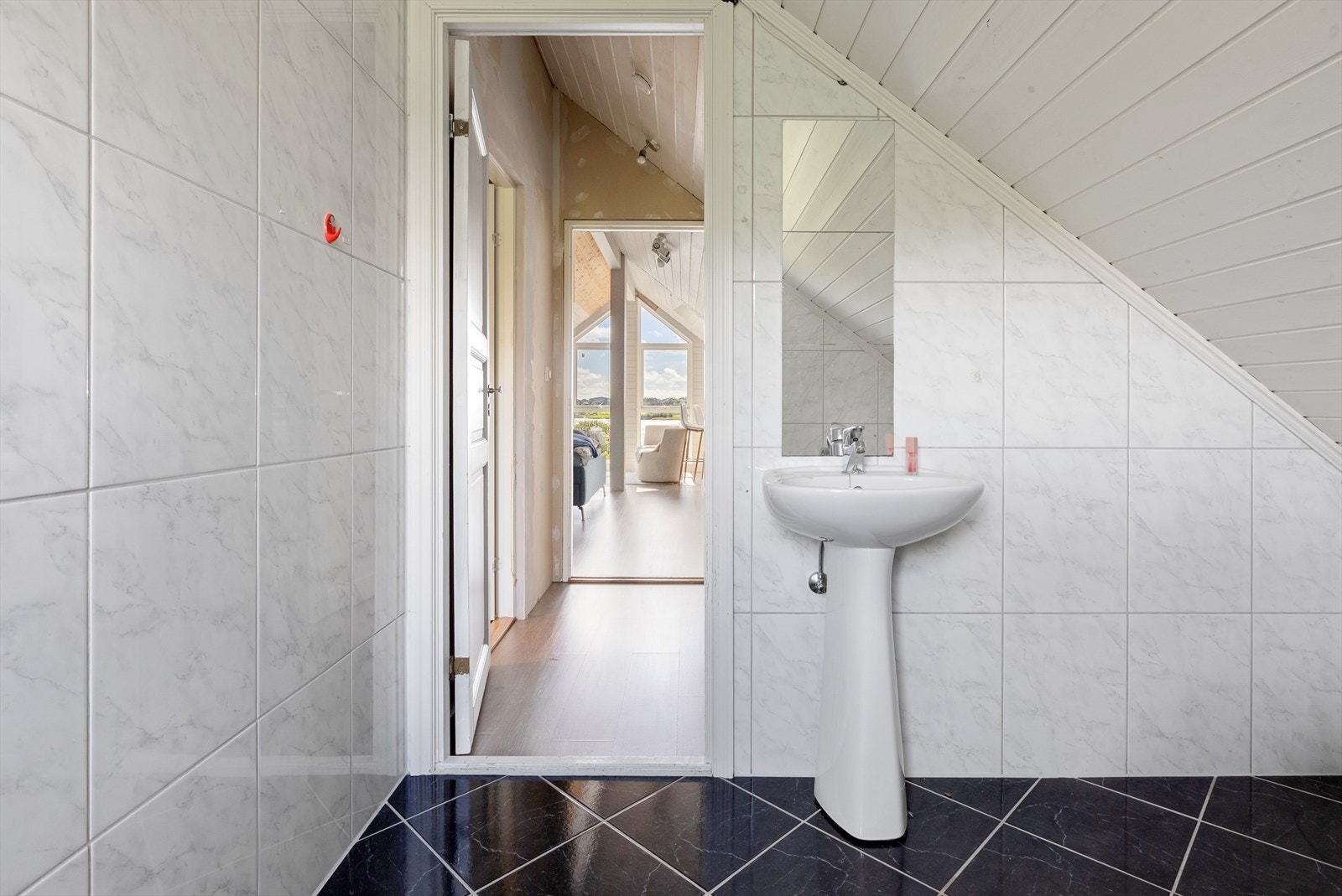 Tilgang til badet fra gang gir en praktisk løsning, og flisbelagte gulv og vegger sikrer enkel vedlikehold. Galleribilde