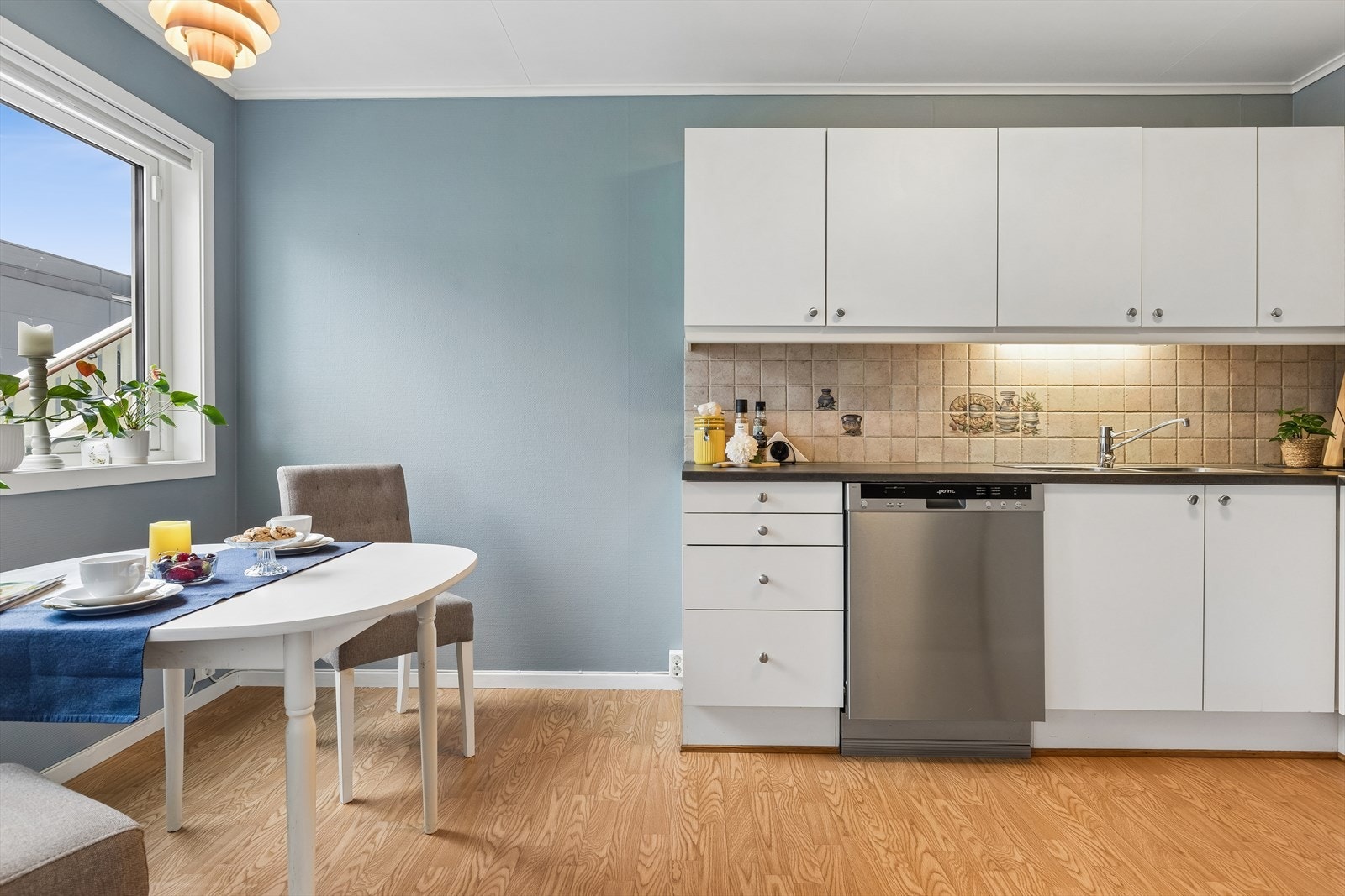 Kjøkkenet ligger i eget rom og fremstår lyst og innbydende med vegger malt i en behagelig blåtone, som står godt til det gylne gulvet. Galleribilde
