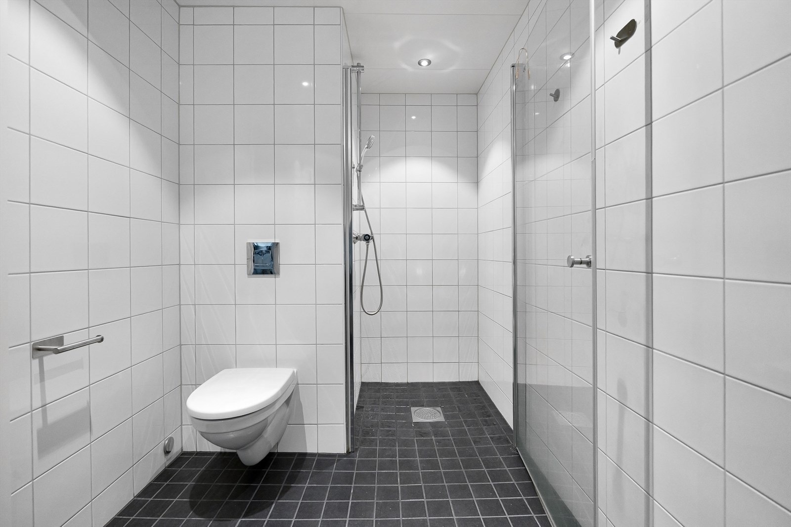 Badet er utstyrt med dusjhjørne, vegghengt toalett, servant med innredning og opplegg for vaskemaskin. Galleribilde