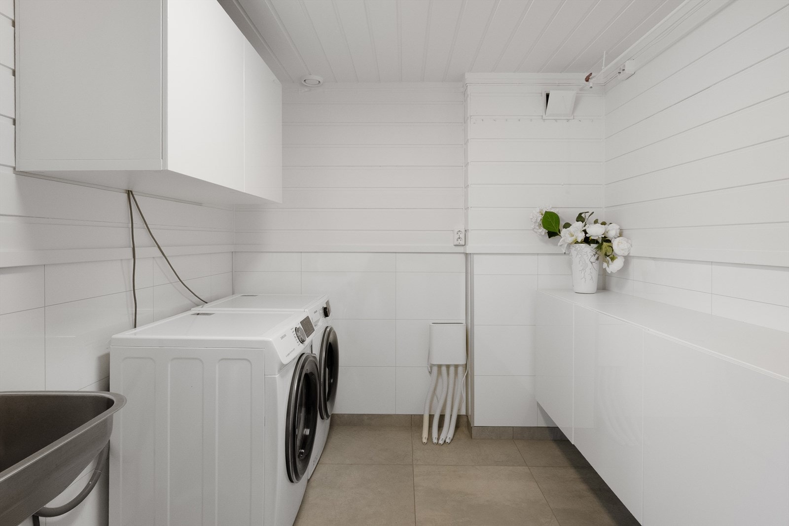 I underetasjen er det et praktisk vaskerom med vegghengt utslagsvask, opplegg for vaskemaskin og vegghengt skap. Galleribilde