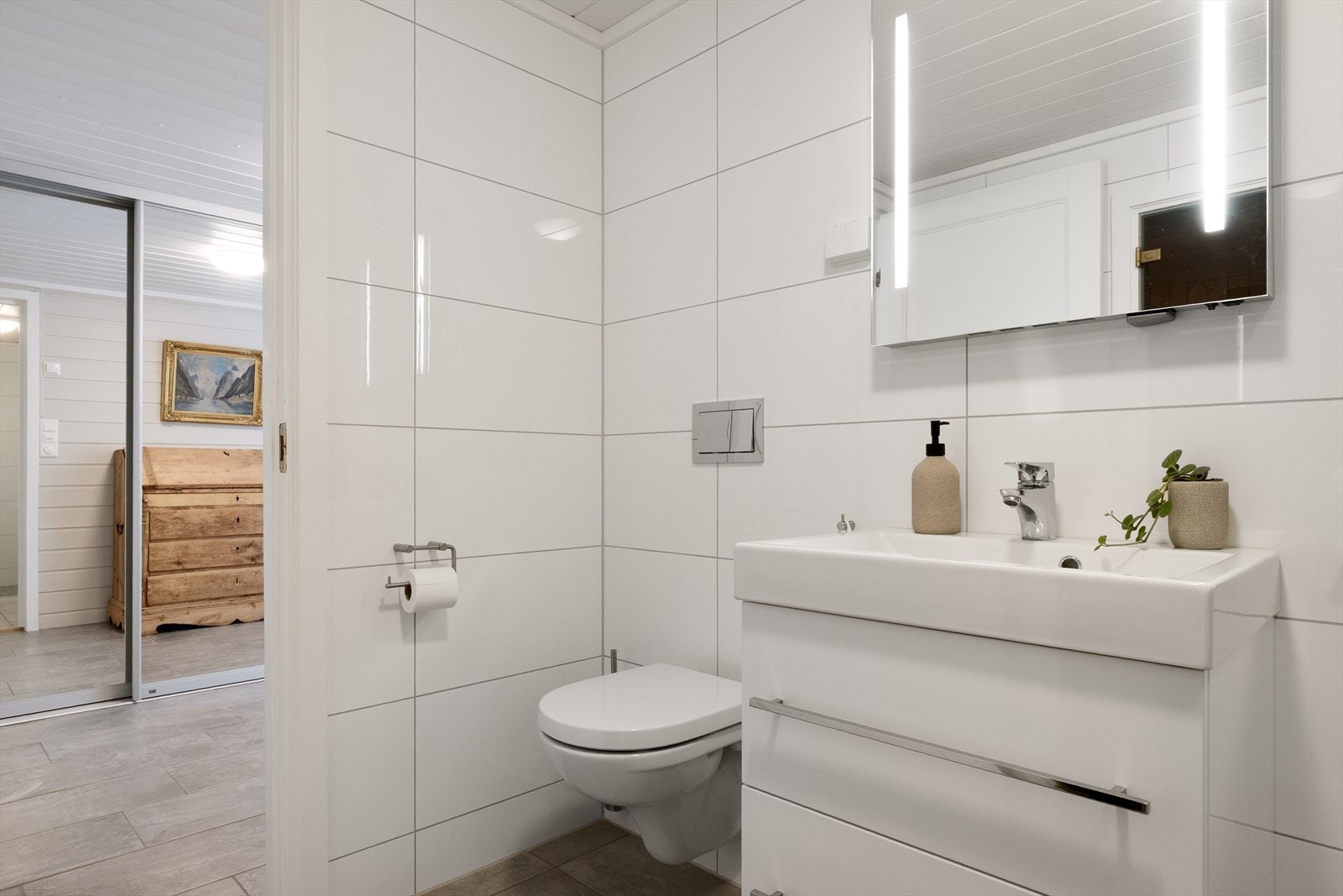Badet har fliser på gulv og vegger, samt malte paneler i himling. Galleribilde