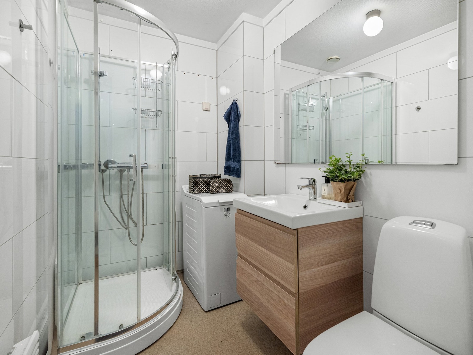 Badet er innredet med toalett, servant med underskap og dusjkabinett. Det er også plass og opplegg for vaskemaskin. Galleribilde