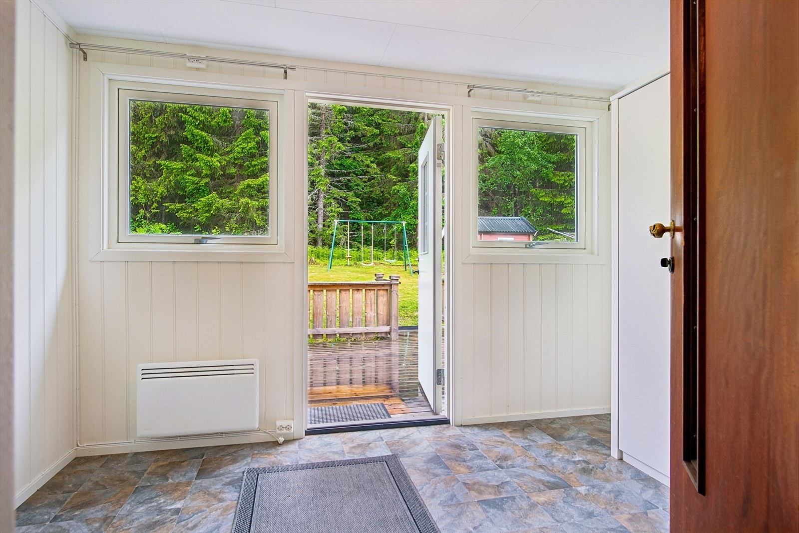 Fra vindfanget er det direkte utgang til en sørvestvendt terrasse i treverk. Galleribilde