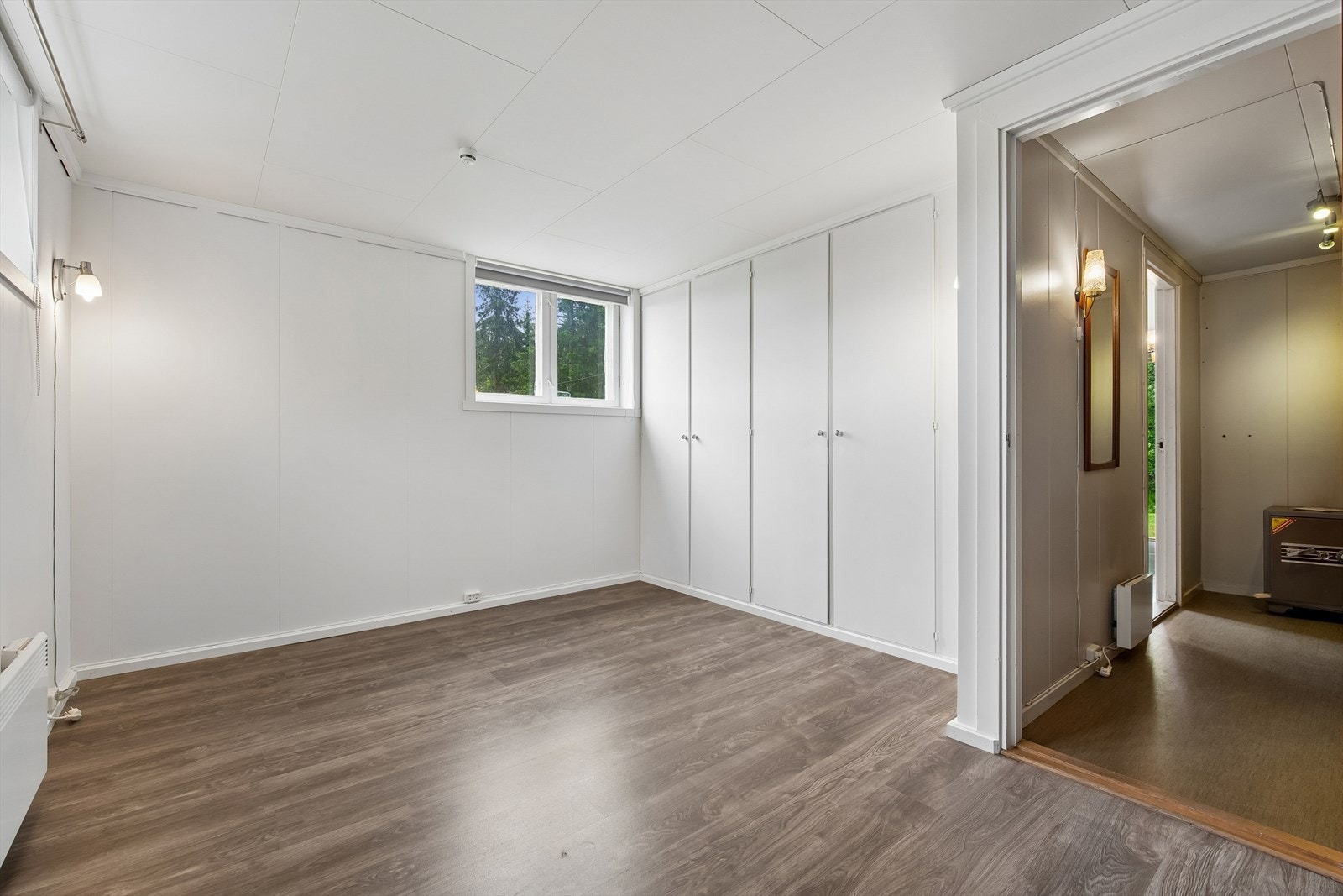Innredet rom i kjelleren med laminatgulv og en hel vegg med garderobeskap. Galleribilde