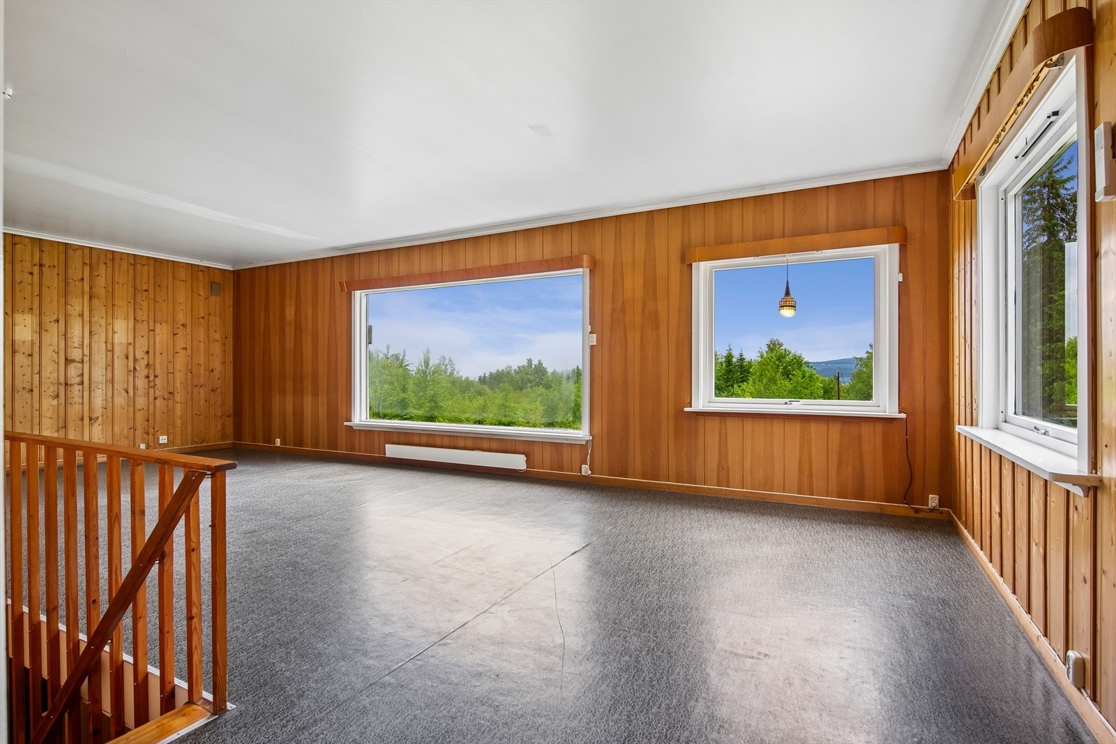 Den ene stuen har store vindusflater og vegger kledd med trepanel. Galleribilde