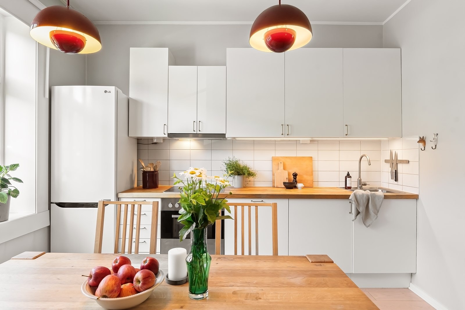 Kjøkkenet har en funksjonell og praktisk utforming, og innredningen består av hvite, glatte fronter, fliser mellom benkeplaten og overskapene samt en benkeplate i heltre. Galleribilde