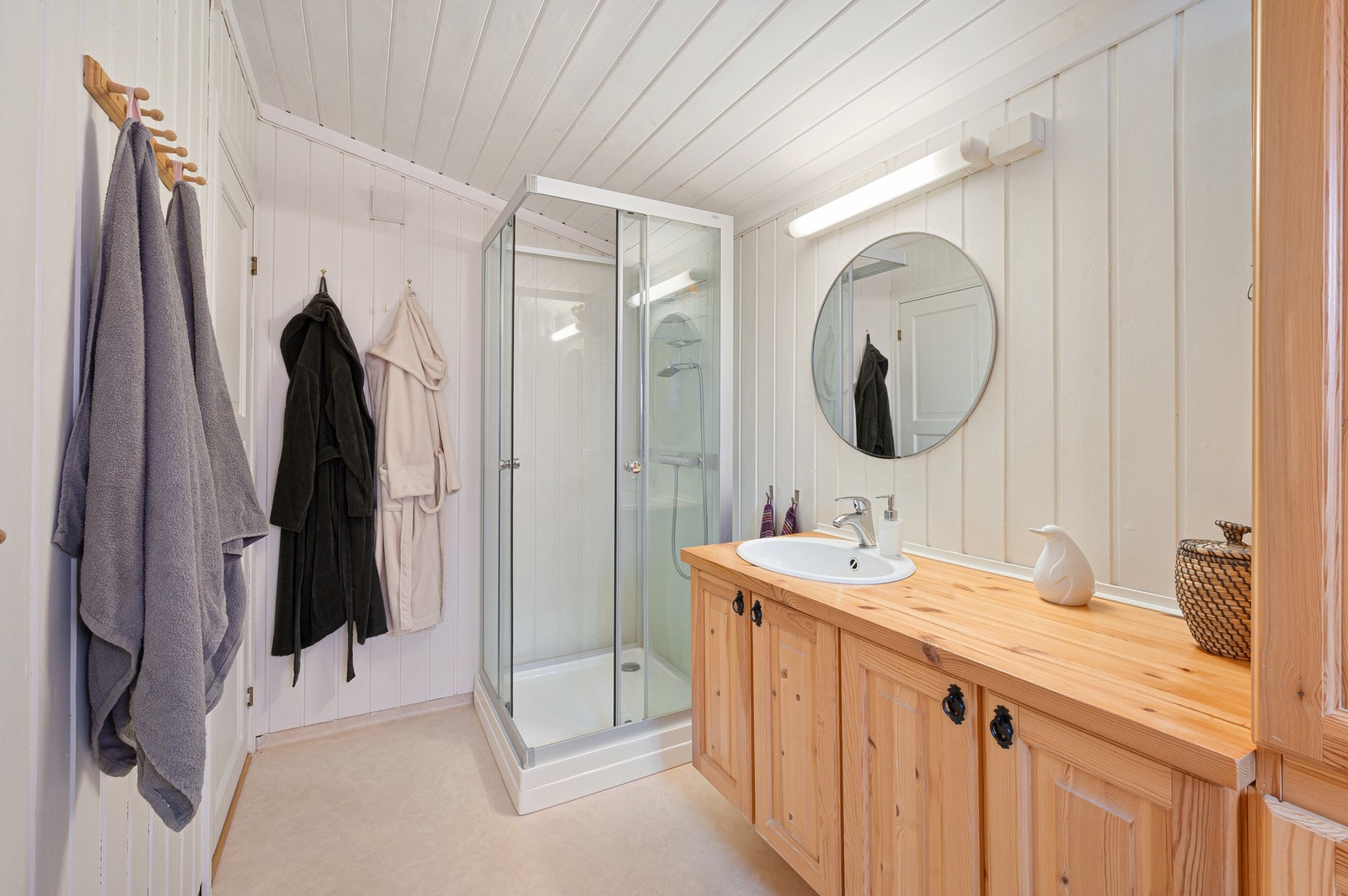 Badet er utstyrt med innredning med profilerte fronter, servant, gulvmontert toalett og dusjkabinett. Galleribilde
