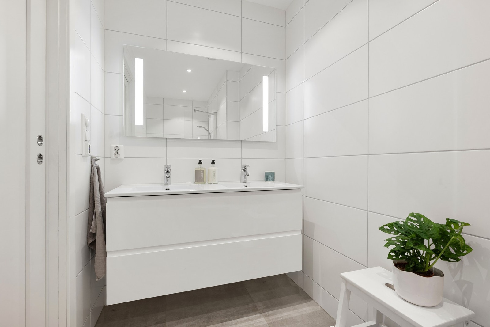 Badet i 1. etasje ligger i tilknytning til TV-stuen og er flislagt med tidløse materialvalg, dobbel servant og varmekabler i gulv. Galleribilde