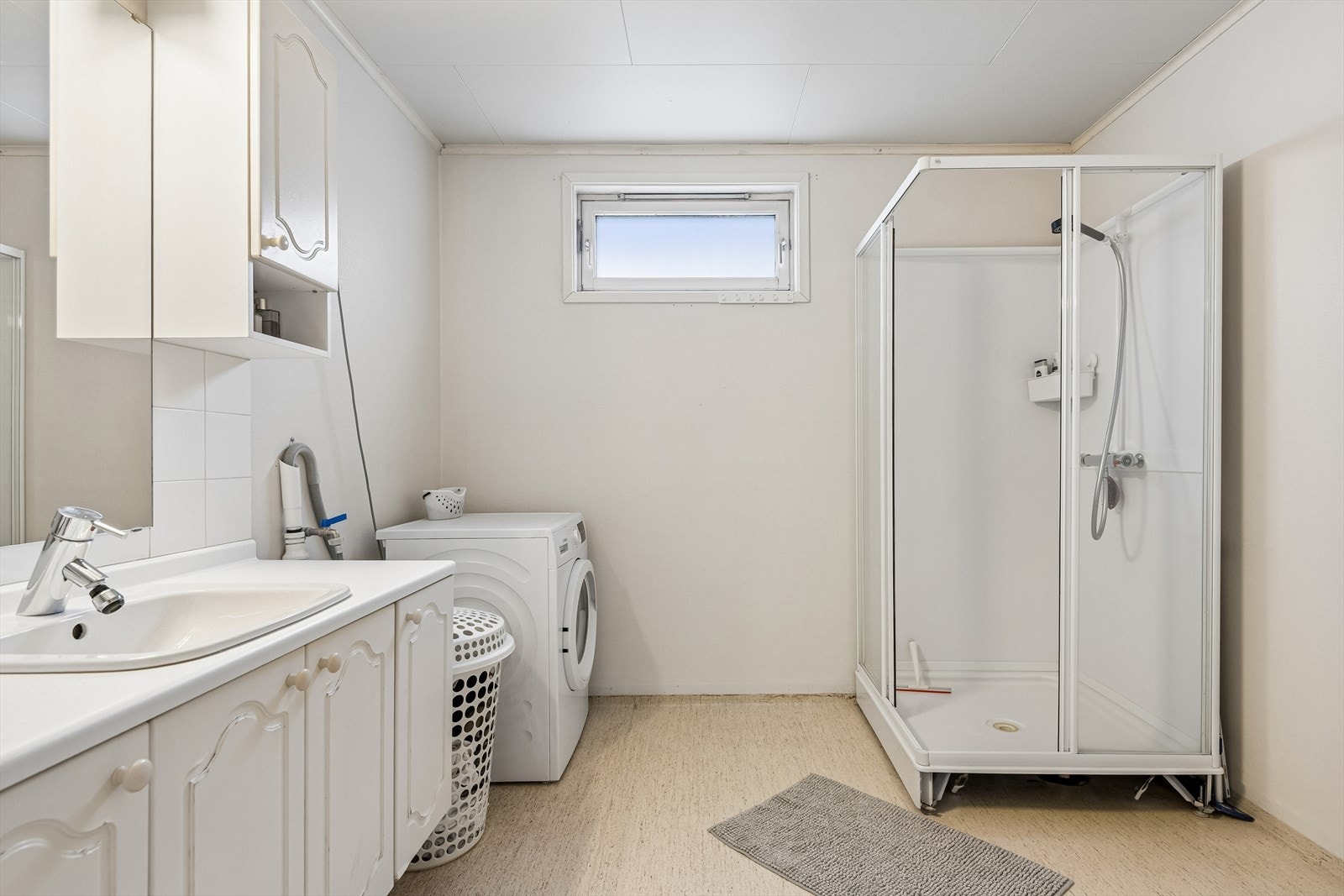 Badet i sokkeletasjen har gulvbelegg, dusjkabinett og opplegg for vaskemaskin. Galleribilde