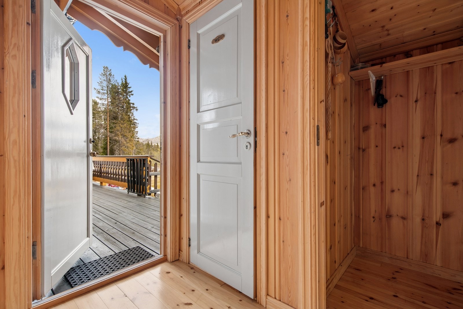 Hytta ønsker velkommen med et praktisk vindfang, utført med panelte flater og lakkert furugulv. Galleribilde