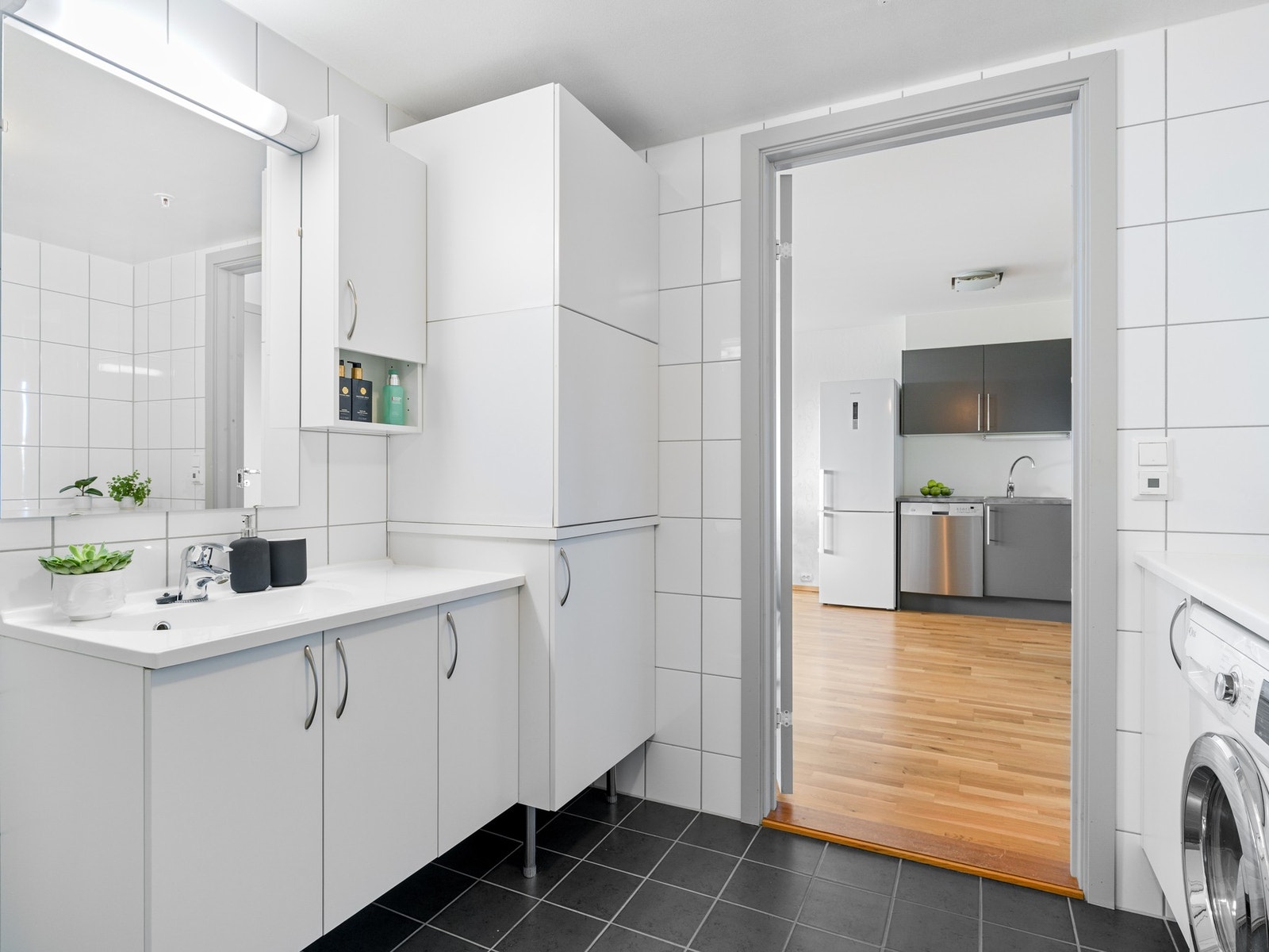 Rommet er innredet med servantskap med gode oppbevaringsmuligheter, toalett og dusjhjørne. Det er i tillegg opplegg for vaskemaskin, samt plass til tørketrommel i praktisk innredning med benkeplate. Galleribilde