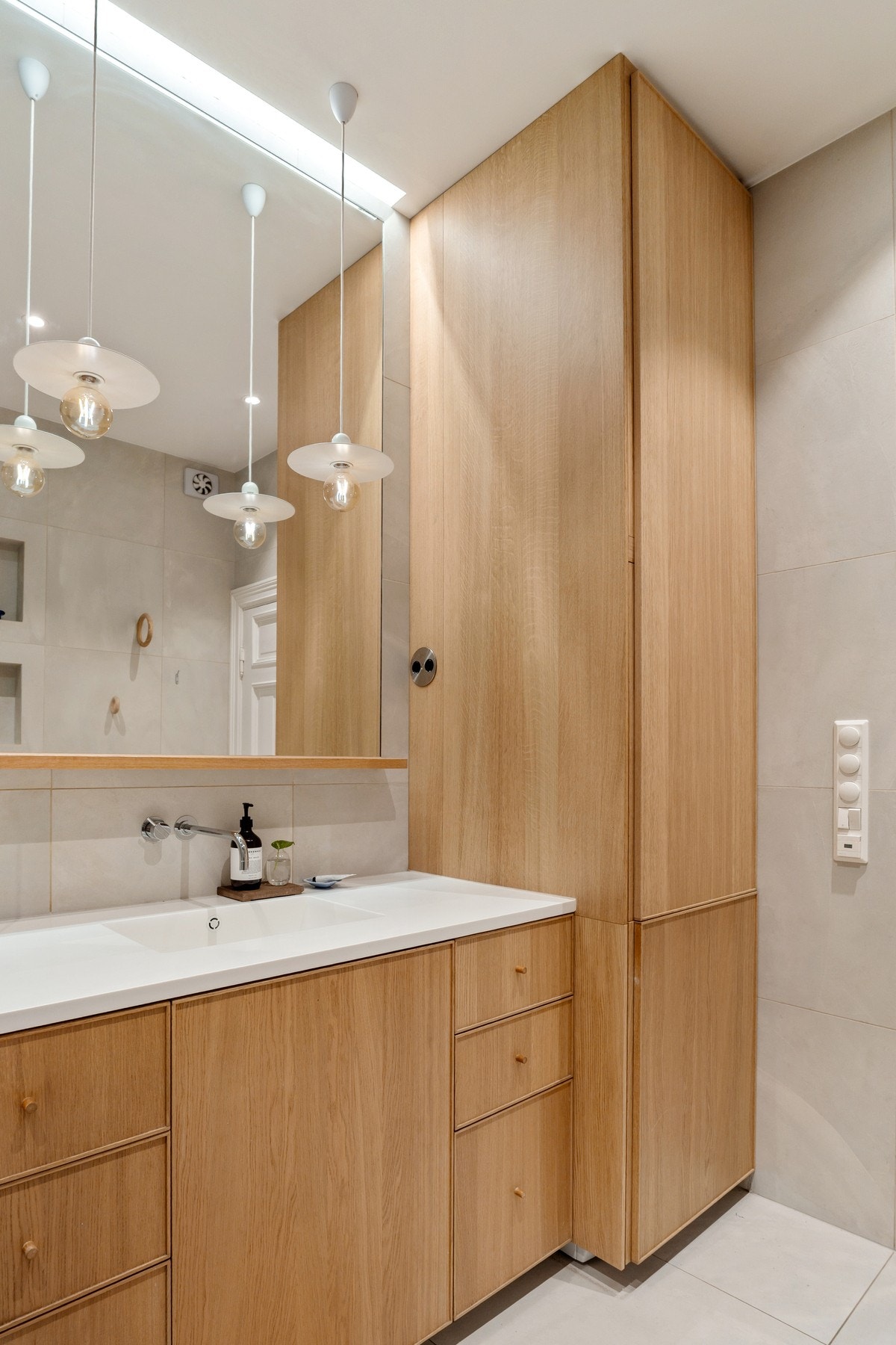 Badet er innredet med servantskap med glatte, finerte fronter, integrert speil i vegg, høyskap med avsatt plass og opplegg for vaskemaskin, innfliset badekar med fastmontert dusjvegg av herdet glass og veggmontert toalett. Galleribilde