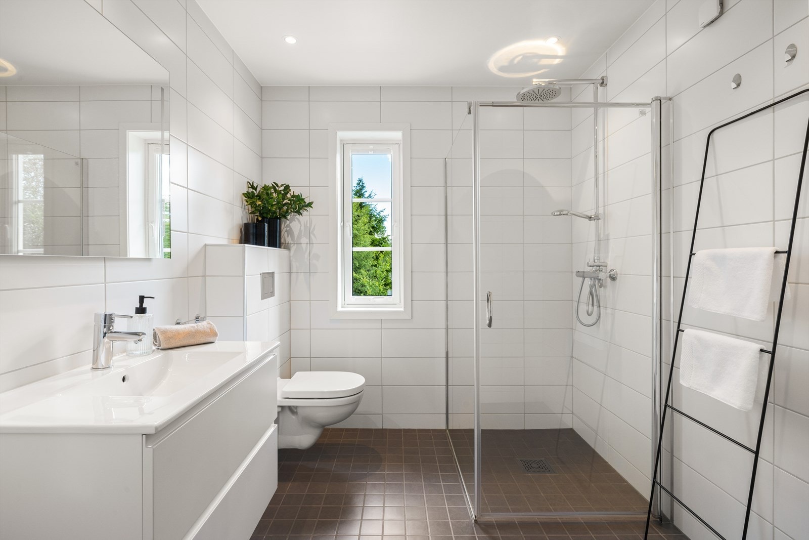 Badet i etasjen er lyst og fint med glassdører, vegghengt toalett og baderomsinnredning. Galleribilde