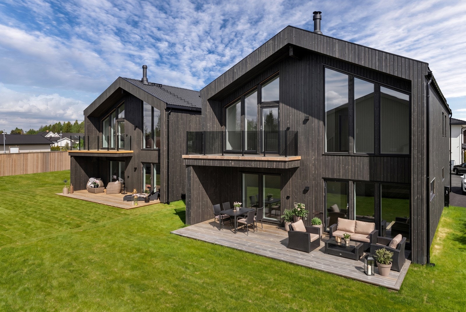 Boligen har en familievennlig planløsning og gjennomførte materialvalg. Uteplass på hus til høyre er KI redigert med utemøbler. Galleribilde