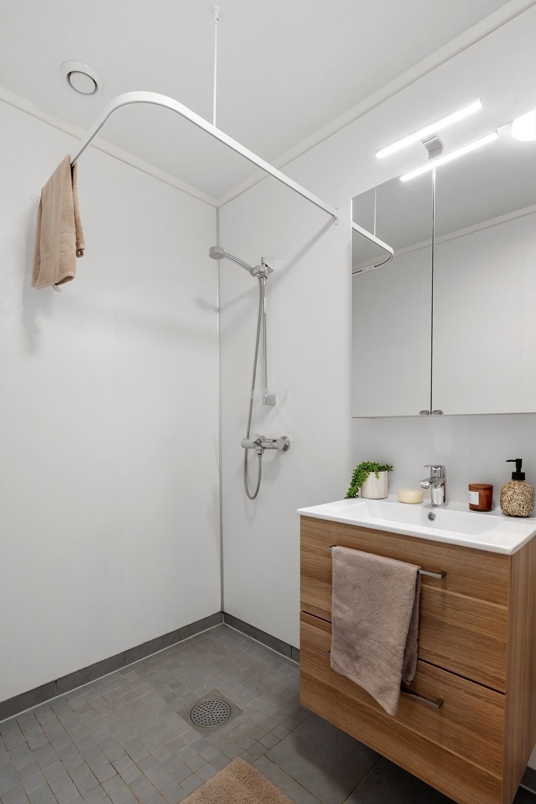 Dusjhjørne, armatur, wc og heldekkende servant med underskuffe og speilskap over. Galleribilde
