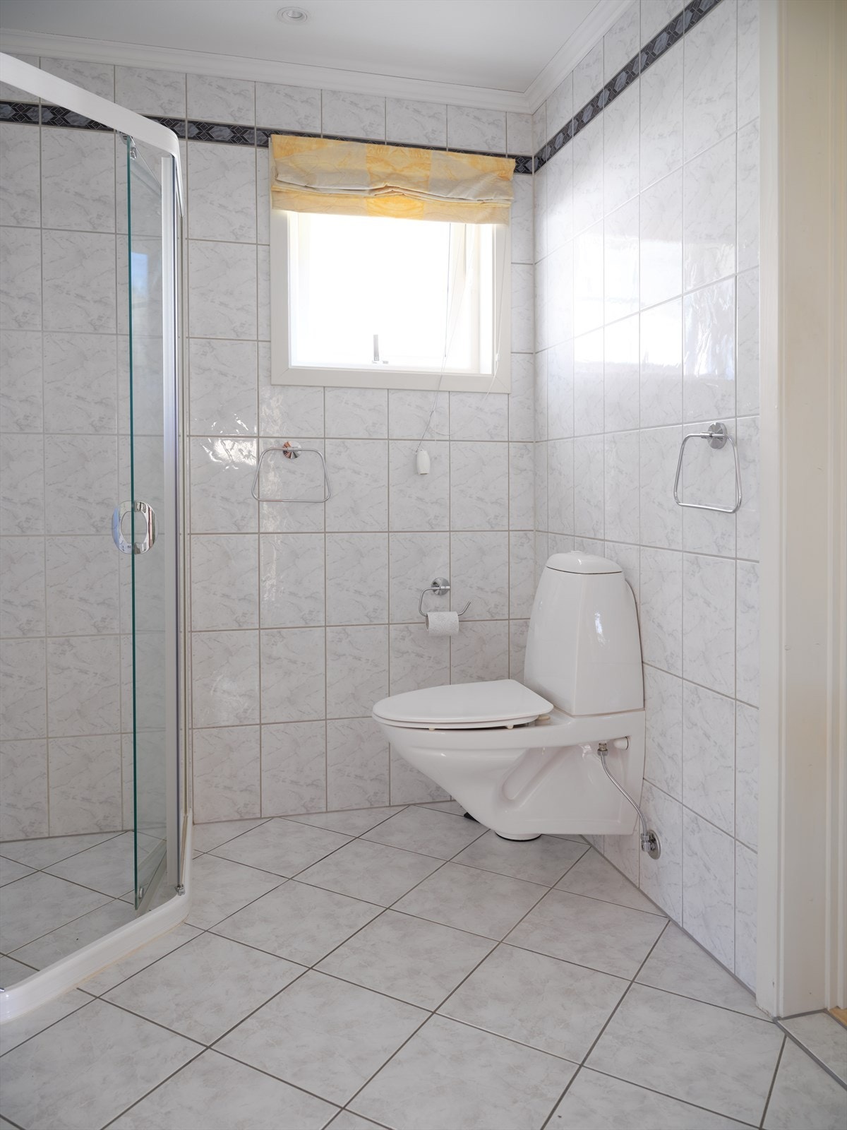 Det andre badet i første etasje har flislagte overflater og vegghengt toalett. Galleribilde